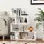 The image features a white bookshelf filled with various items, including books, a vase, a potted plant, and a teddy bear. The bookshelf is situated next to a couch, and there is a picture on the shelf. The scene is set in a living room, with a cozy and inviting atmosphere.