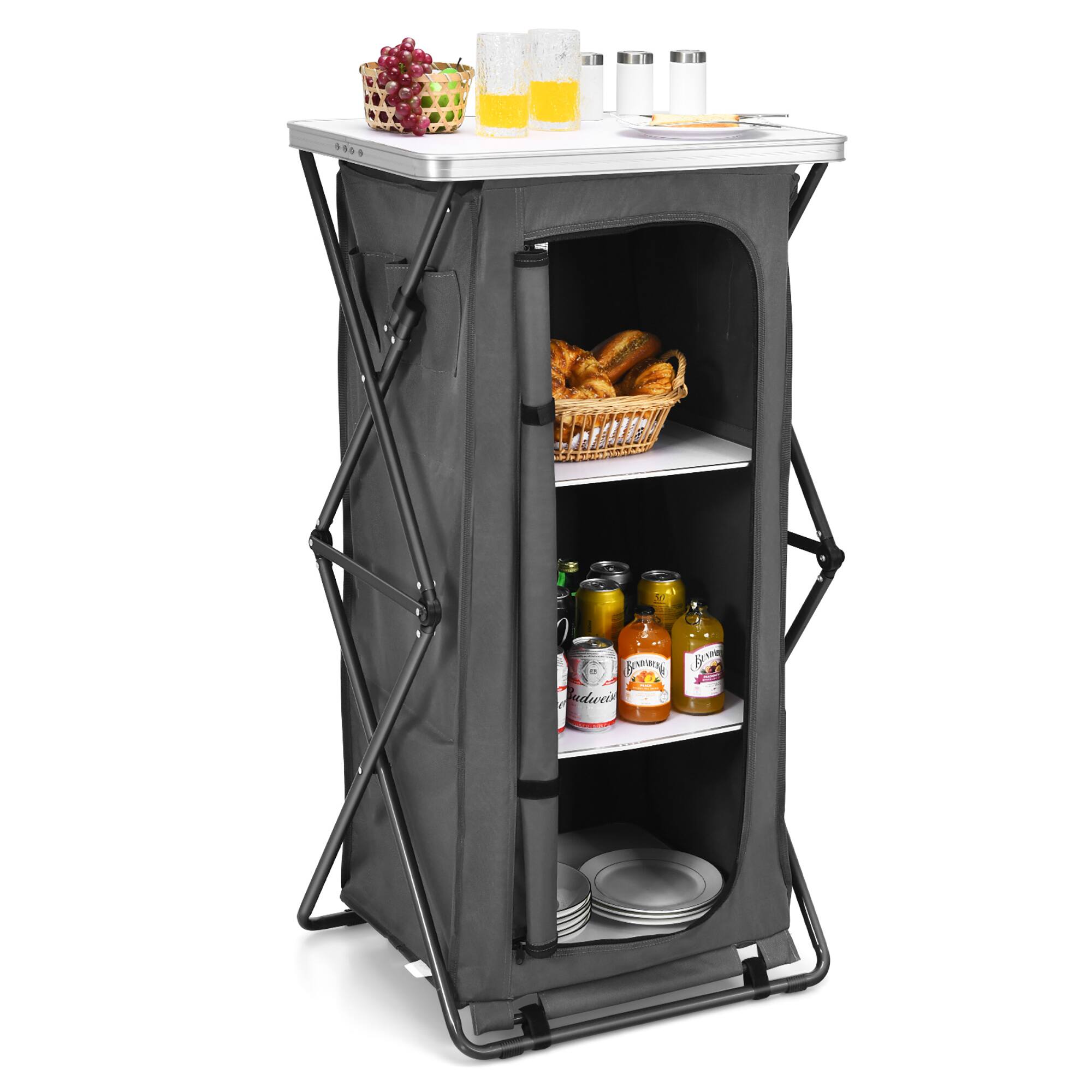 The image shows a small refrigerator with a basket of bread and a few bottles of condiments inside. The refrigerator is placed on a table, and there are also a few cups and a bowl nearby. The scene suggests that it is a small kitchen setup, possibly for a picnic or a similar outdoor event.