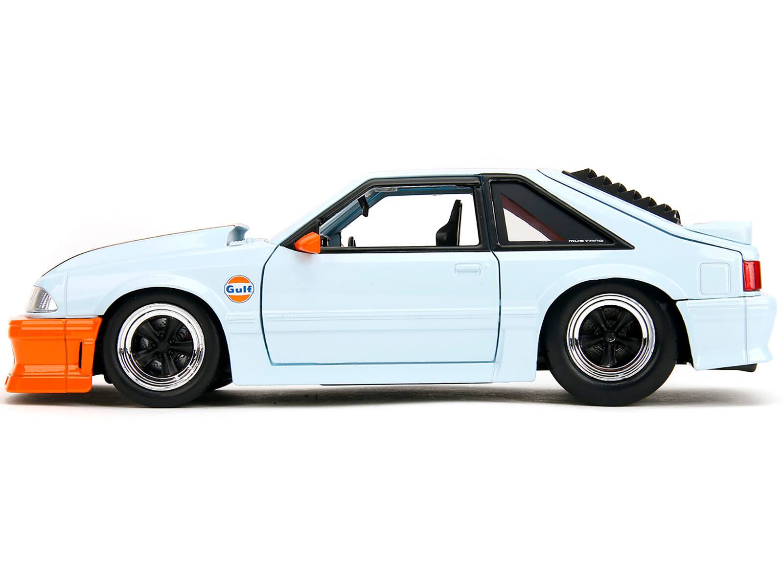 Left. Jada - 1989 Ford Mustang GT "Gulf Oil" Light Blue with Orange Stripe "Bigtime Muscle" Series 1/24 Diecast Model Car by Jada - Light Blue And Orange Stripe.