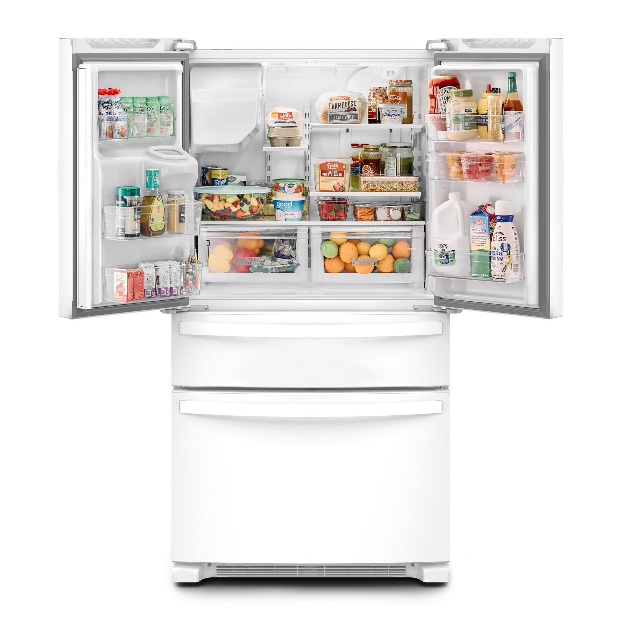 The image shows a refrigerator with its door open, revealing a variety of food items inside. There are several bottles, including milk and juice, placed on different shelves. The refrigerator also contains a variety of fruits, such as apples and oranges, as well as a bowl of fruit. Additionally, there are a few cups and a spoon visible in the refrigerator. The refrigerator is filled with a diverse assortment of food items, making it a well-stocked and functional appliance.