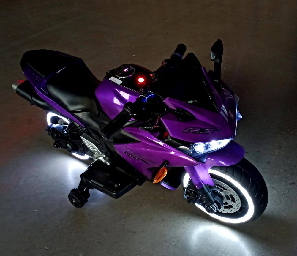 Angle. BreeBe - 12V Kids Motorcycle Ride On Toy w/ Training Wheels, Manual Throttle, Hand Drive, Lights, for Boys & Girls Ages 3-6 - Purple.