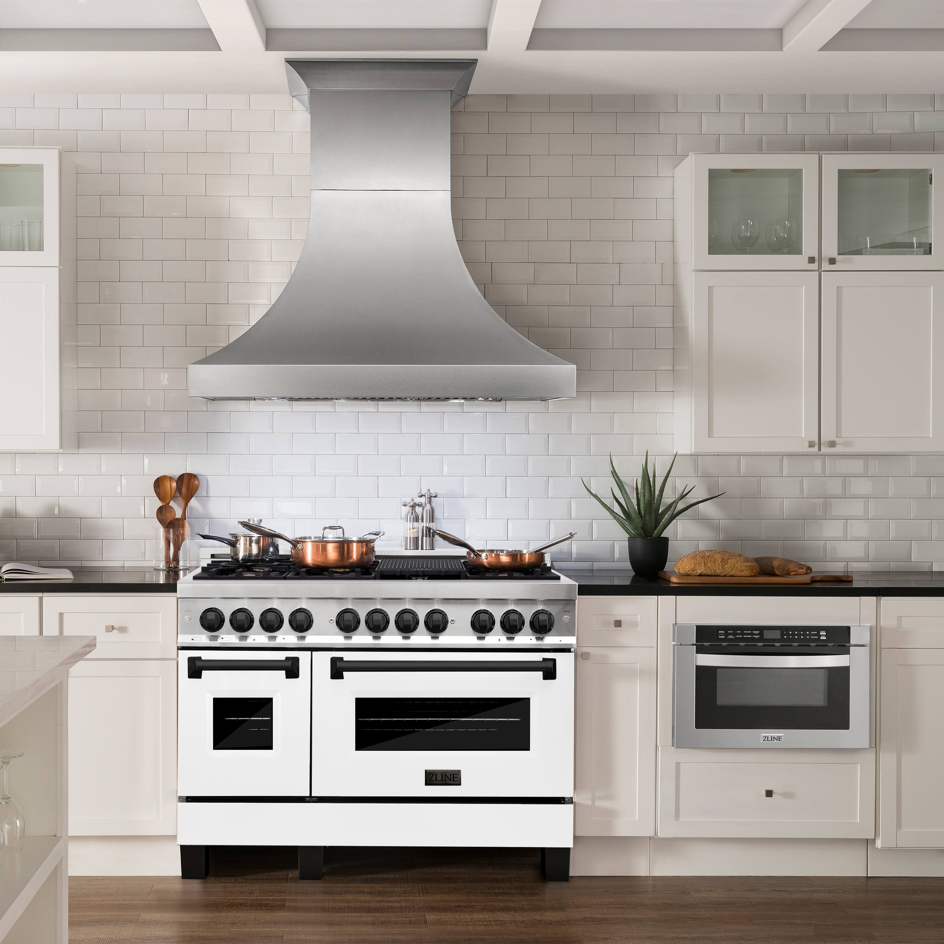 The image features a kitchen with a white stove top oven and a vent hood above it. The oven is positioned under a stove hood, which is a modern design element that helps to remove heat and smoke from the cooking area. The kitchen also has a black and white color scheme, with white cabinets and a black stove. 

In addition to the stove, there are several kitchen utensils and items present in the scene. There are two knives, one located on the left side of the stove and the other on the right side. A spoon can be found on the left side of the stove as well. 

There are also two bowls in the kitchen, one placed on the right side of the stove and the other on the left side. A potted plant is situated on the right side of the stove, adding a touch of greenery to the space. Finally, there is a book located on the left side of the stove, possibly containing recipes or other cooking-related information.