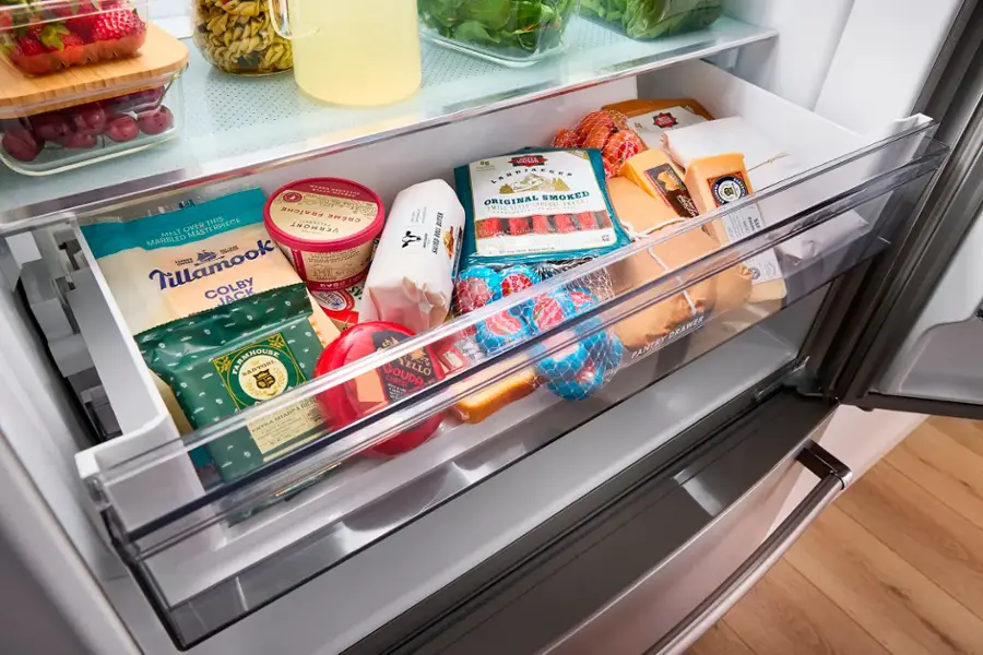 The refrigerator is filled with various food items, including cheese, milk, and juice. There are multiple bottles of juice, milk, and cheese in the refrigerator. The refrigerator is also stocked with fruits and vegetables, such as strawberries and broccoli. The refrigerator is well-organized, with the food items placed in different compartments, making it easy to find and access the desired items.