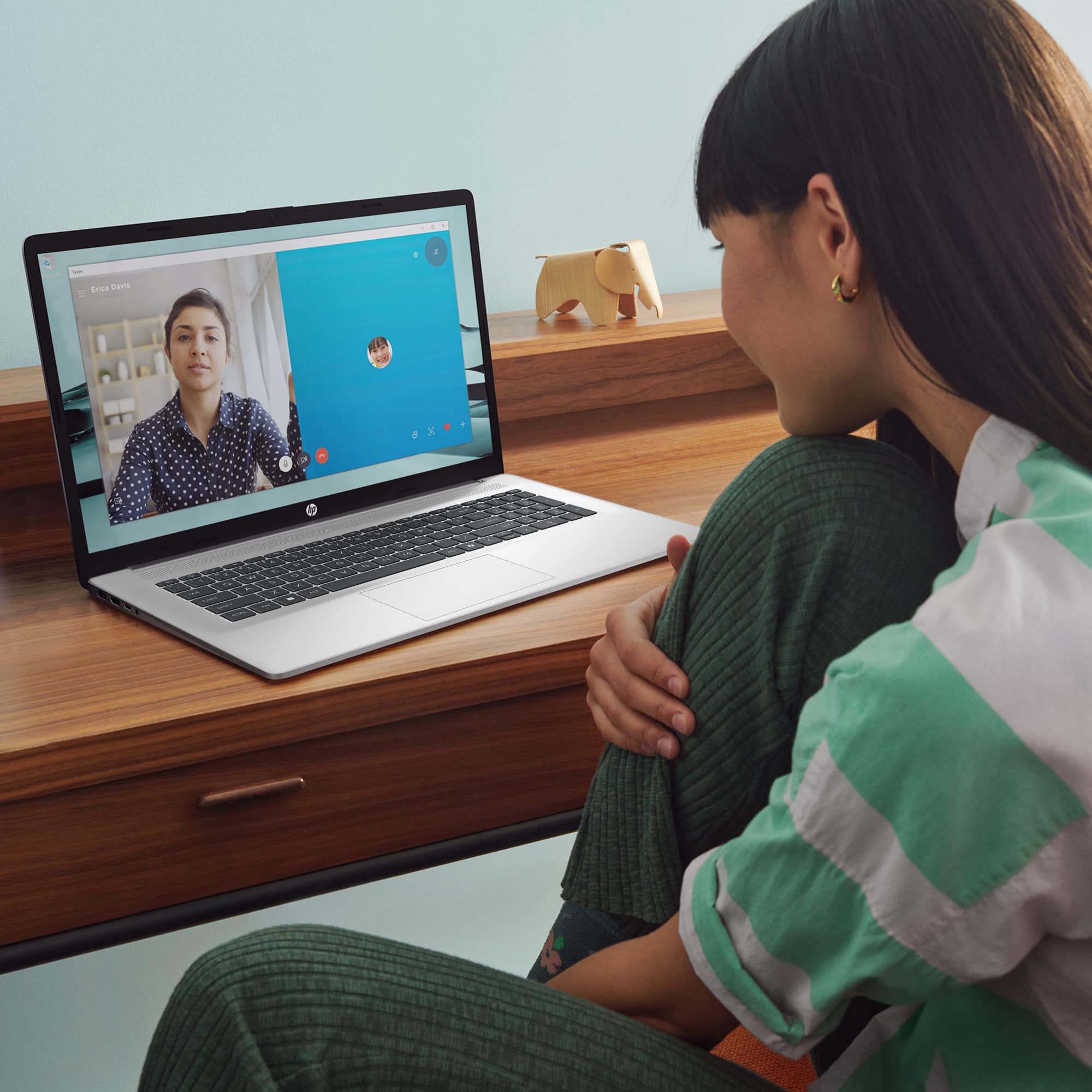 I'm sorry, but the image does not contain any text that can be grouped or corrected. The image shows a woman sitting in front of a laptop computer, with the laptop screen displaying a man's face. The woman is wearing a striped shirt and has her hands on her chin.