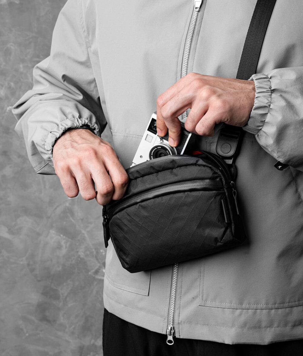 Alt View 3. ALPAKA - Flight Sling 1L Travel Sling Bag, Lightweight Crossbody Pouch, Phone Sleeve, Passport Pocket, Detachable Strap - Black Ultradyne 100D.