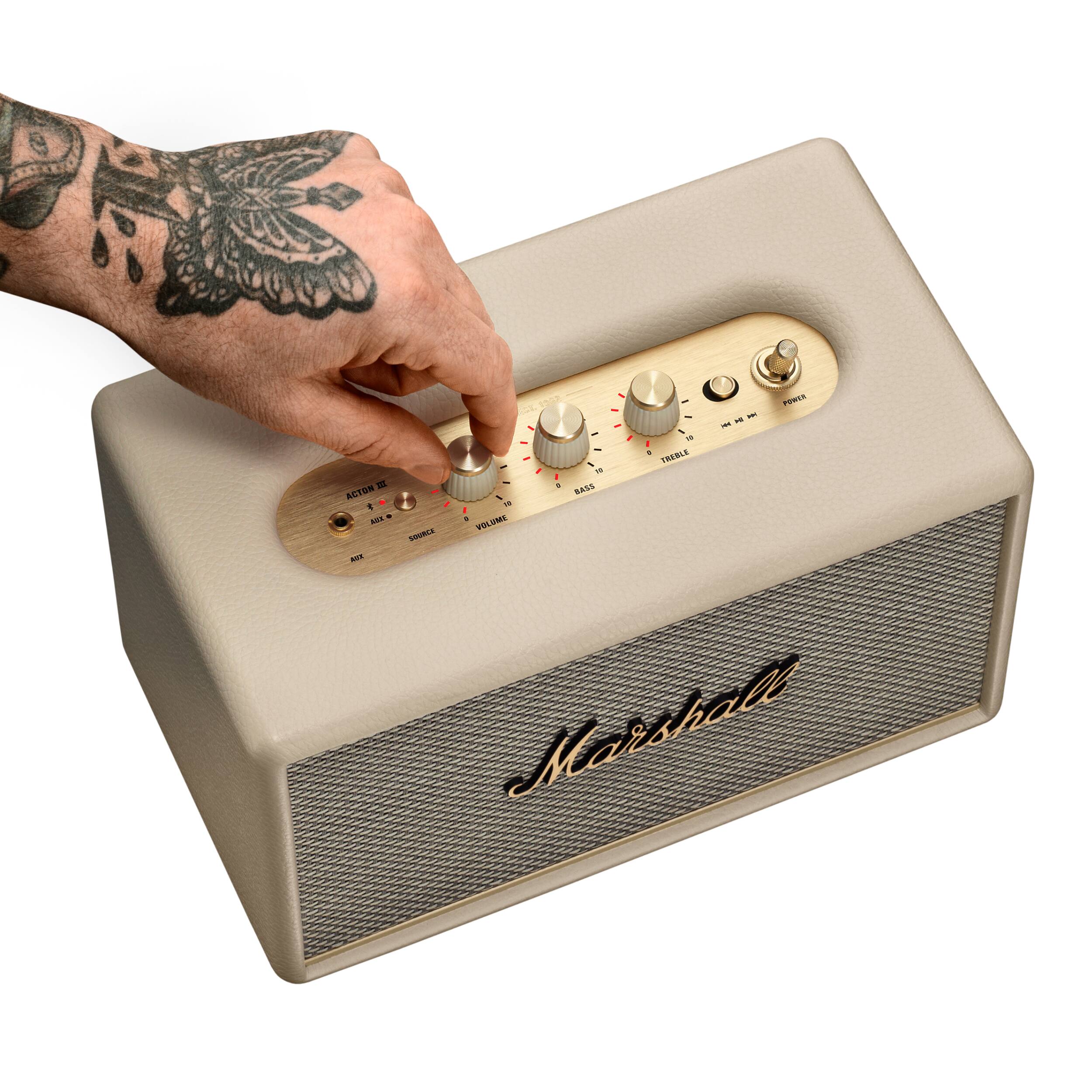 A hand is pressing a button on a Marshall speaker.