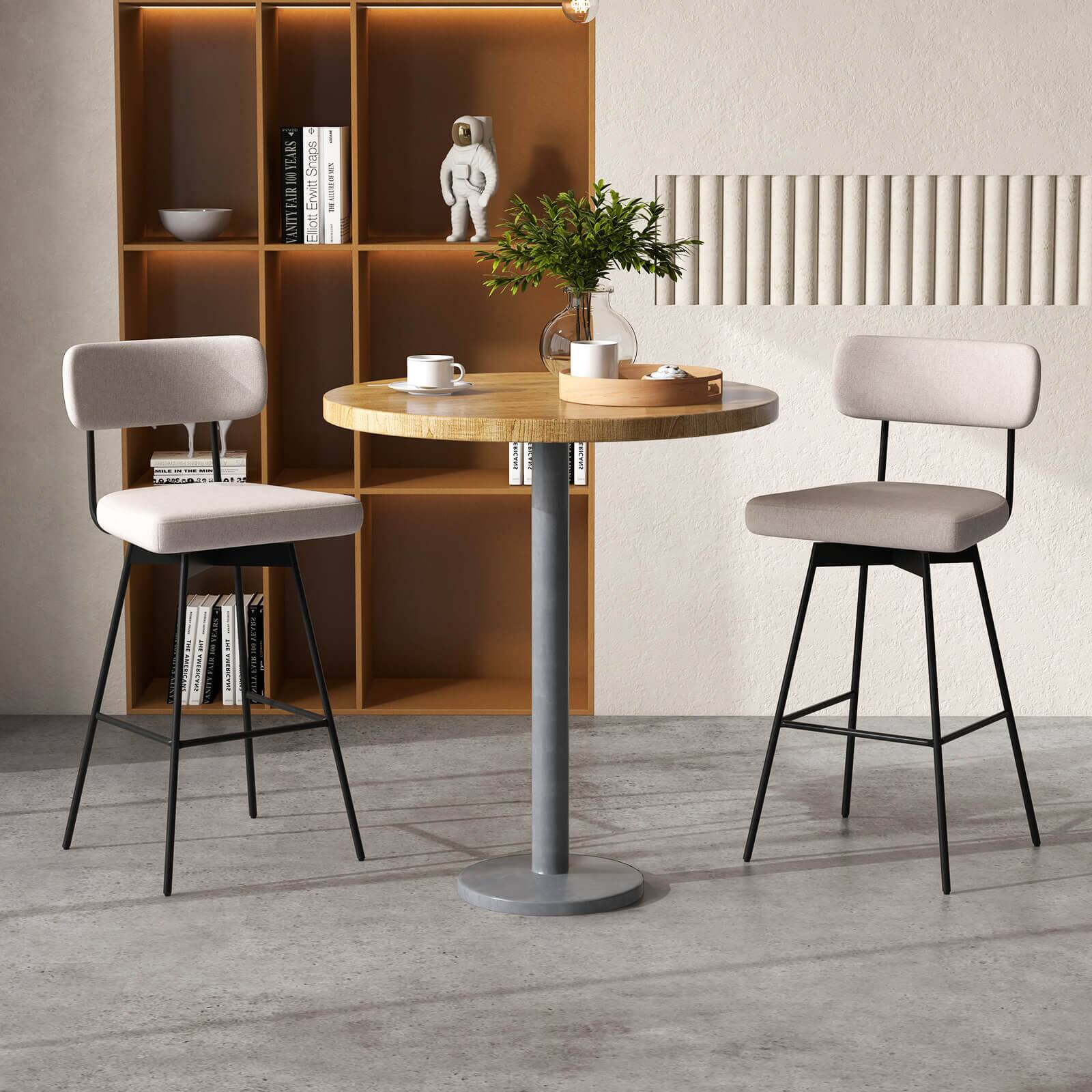 The image features a table with a vase of flowers on it, surrounded by three chairs. The table is placed near a bookshelf, which has several books on it. The chairs are positioned around the table, creating a cozy and inviting atmosphere. The scene appears to be a comfortable and pleasant space for people to gather and enjoy each other's company.