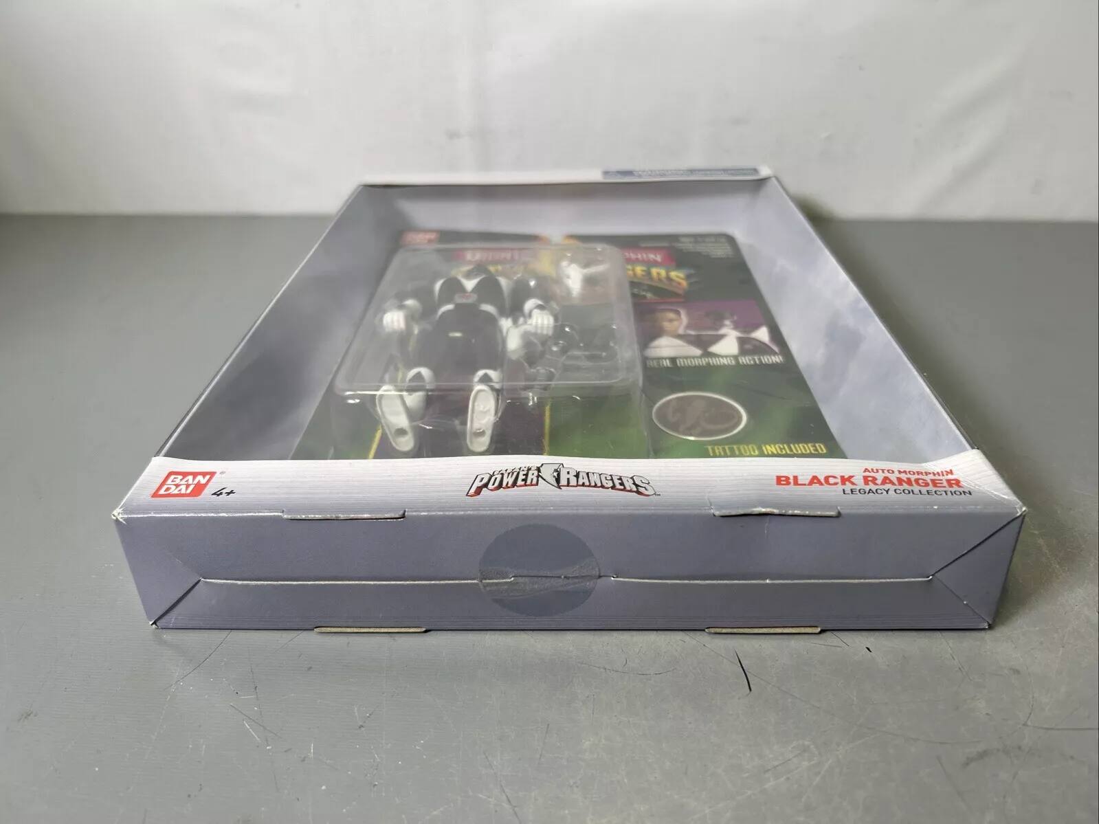 The text on the image should be grouped and corrected as follows:

"Power Rangers: Black Legacy Collection - Auto Morphin Rangers, 4+ Tattoo Included."

This refers to a collection of action figures from the Power Rangers series, specifically the Black Legacy Collection, which includes figures with auto-morphing features and a tattoo accessory.