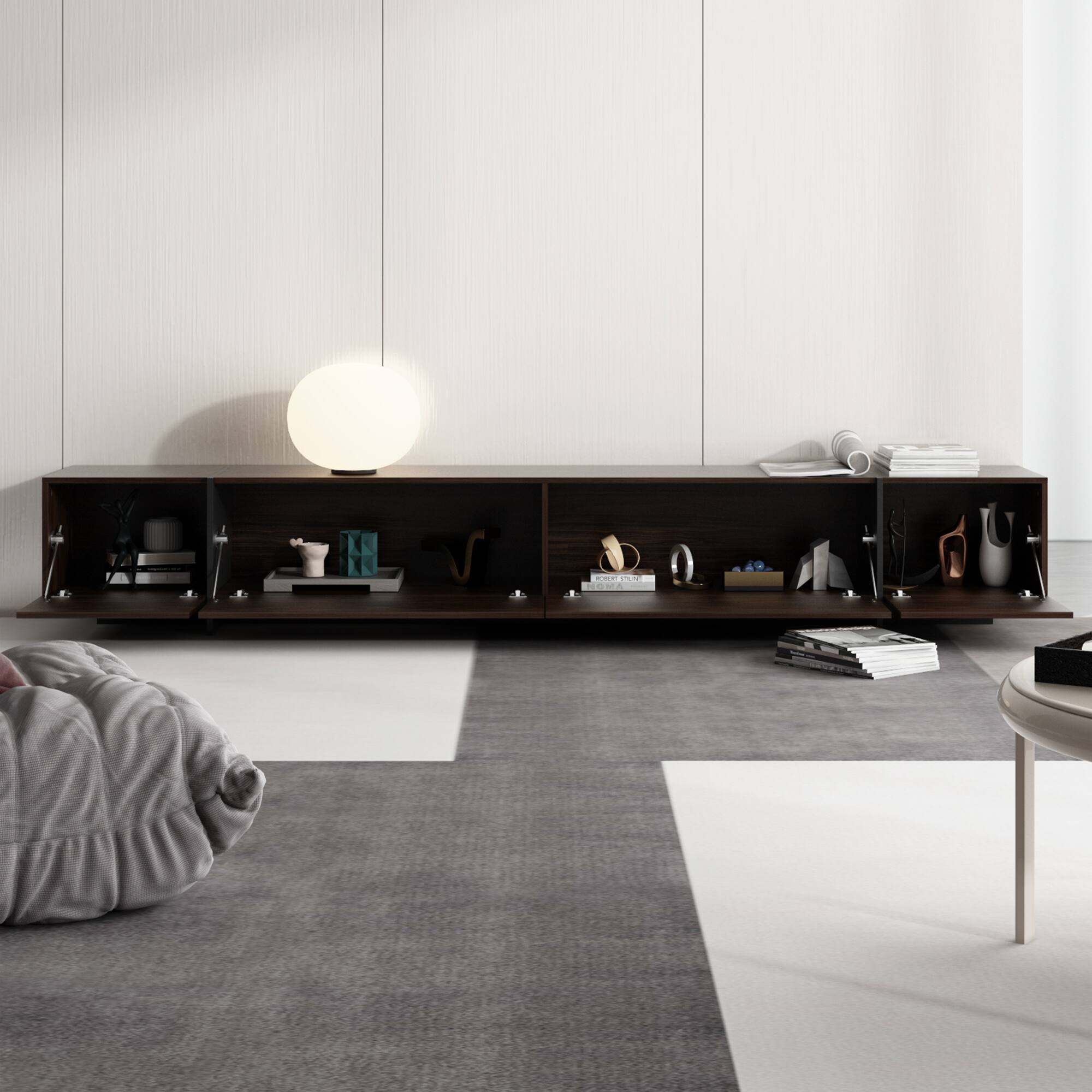 There is no text on the image. The image shows a living room with a couch, a coffee table, and a bookshelf. The room is decorated with various items, such as a lamp, a vase, and a clock. The couch is placed in front of the bookshelf, and the coffee table is located near the couch. The room has a clean and organized appearance, with a grey carpet adding to the overall aesthetic.