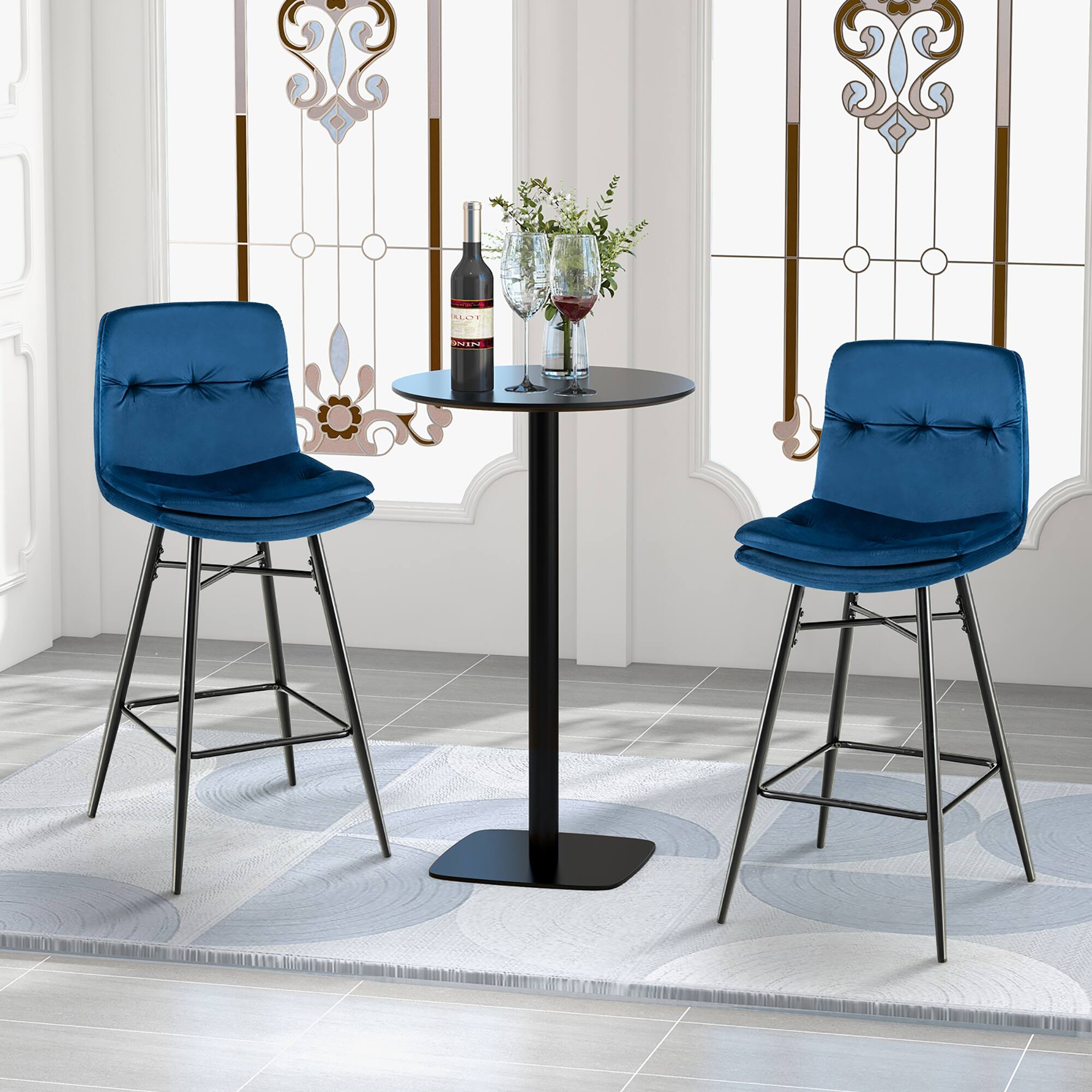 "Two blue chairs are placed around a small table with a bottle of wine and two wine glasses on it. The chairs are positioned in front of a window, and there are two vases on the table as well. The table is black, and the chairs are blue. The scene is set in a room with a rug on the floor."