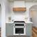 I have a large kitchen with a stove top oven, a microwave, and a sink. The oven is white and has a black door. The kitchen also features a wood floor and a counter with a potted plant on it. The counter also has a vase and a cup. The kitchen is well-equipped for cooking and food preparation.