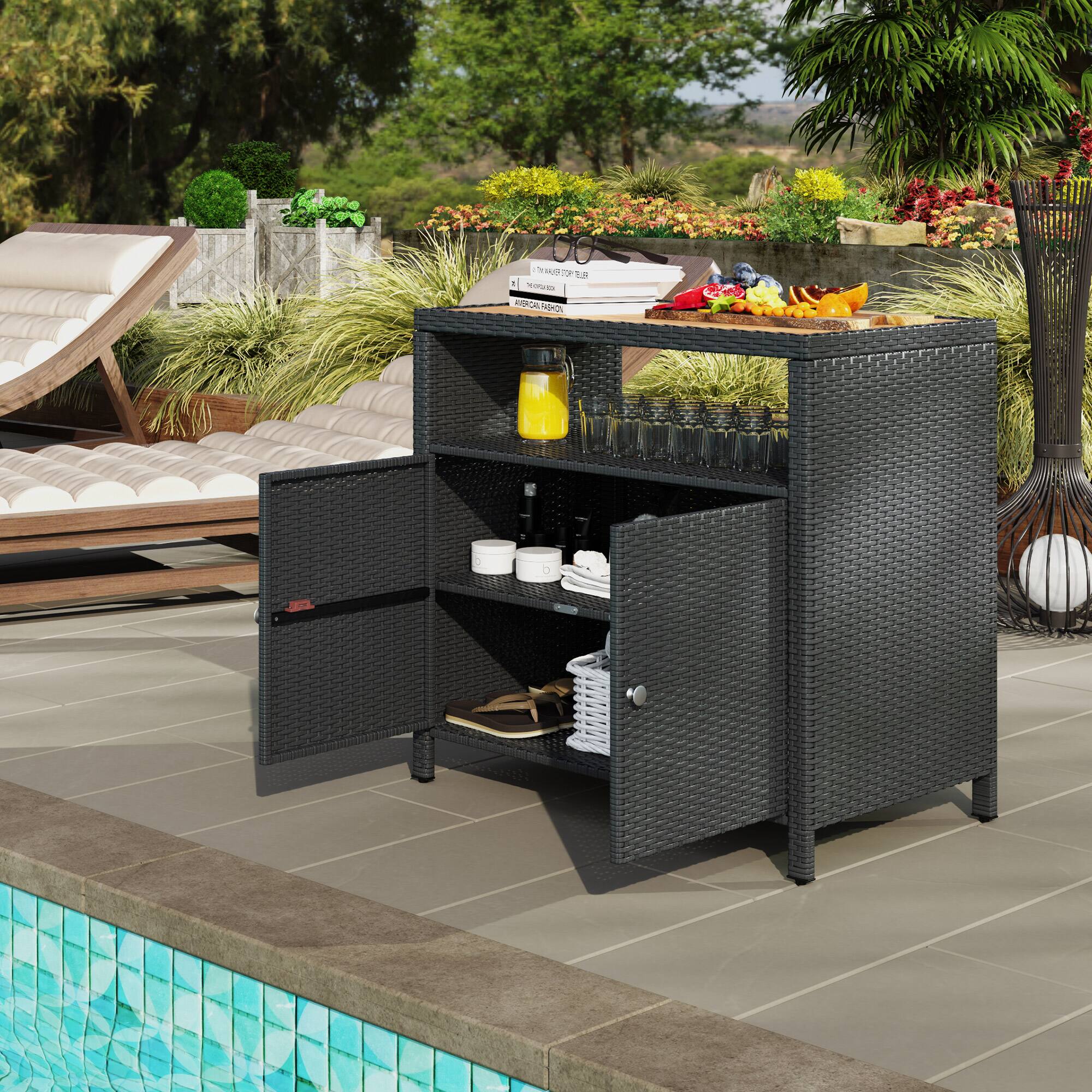 The image shows an outdoor setting with a wicker bar cart near a pool. The cart has a yellow pitcher, glasses, and a fruit bowl on top. There are loungers and greenery in the background.