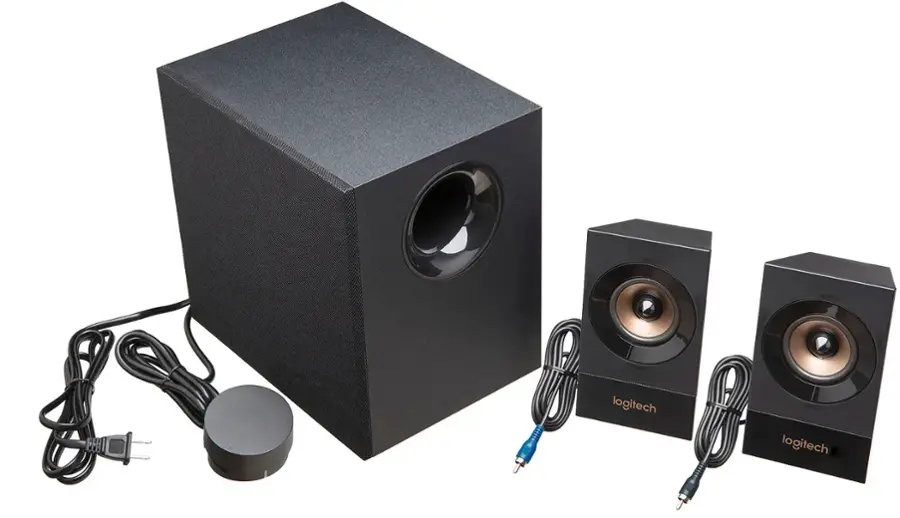 The image features a black speaker system from the brand Logitech. The system includes a subwoofer and two satellite speakers, all placed on a white background. The speakers are connected to the subwoofer using cords, and there is a remote control nearby. The setup appears to be ready for use, providing a complete audio solution for a user's entertainment needs.