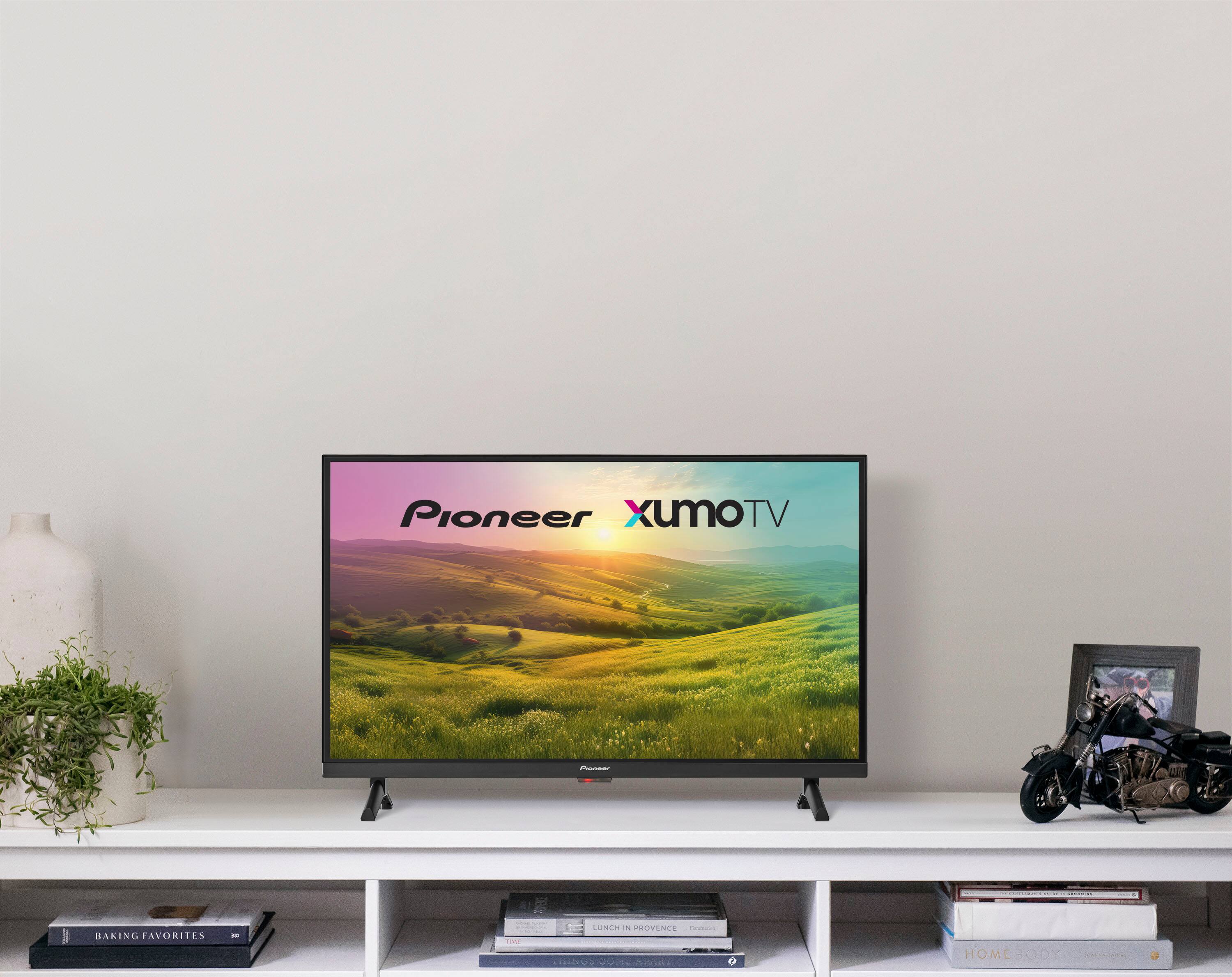 Pioneer XUMOTV is displayed on a large television screen. The screen is set up on a table, and there are books and a potted plant nearby. The television is turned on, and it is likely that the viewer is watching a show or movie.