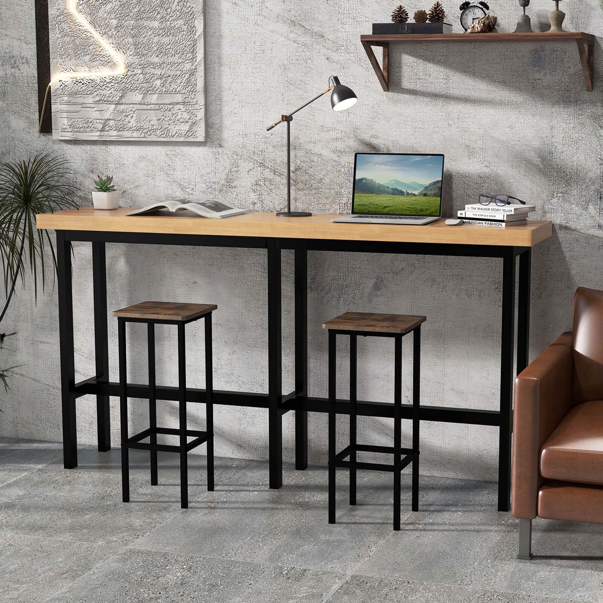 The image shows a desk with a laptop, a lamp, and two stools. The desk is made of wood and has a shelf above it. There are also two books and a potted plant in the scene. The desk is located in a room with a chair and a couch. The room also features a wall with a painting on it.