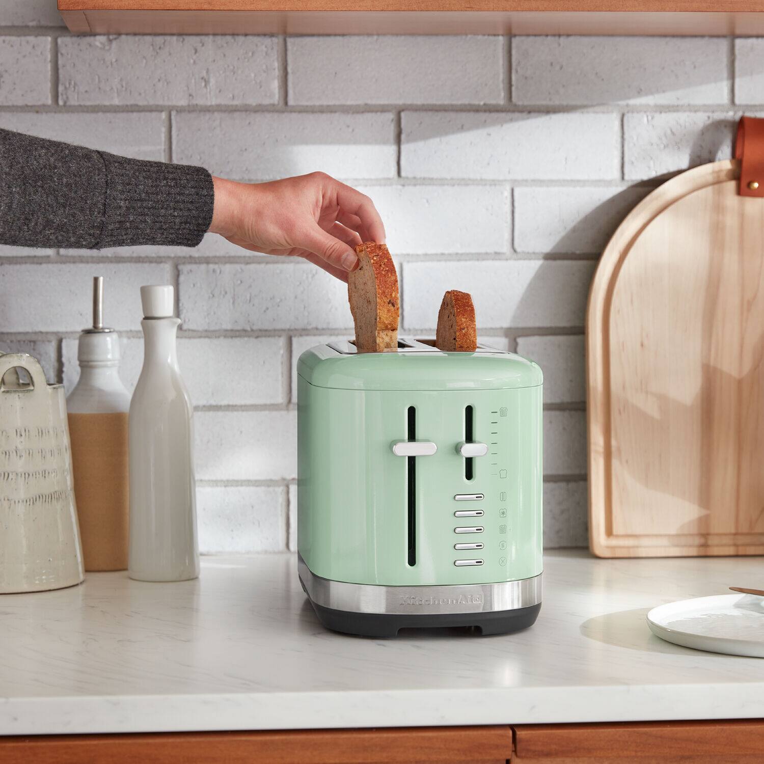 A person is holding a piece of bread in a toaster oven.