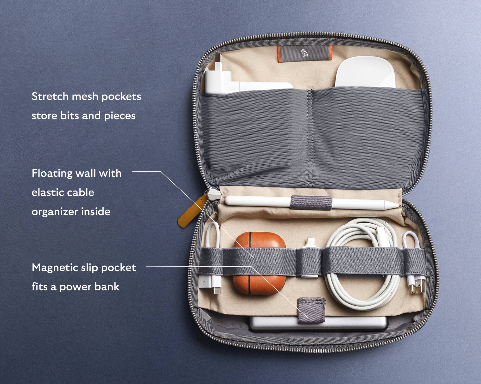 The image shows a small bag with various items inside, including a power bank, a ball, and a laptop. The bag is described as having stretch mesh pockets for storing small items, a floating wall with an elastic cable organizer inside, and a magnetic slip pocket that fits a power bank. The bag is also described as having a pocket for storing bits and pieces.