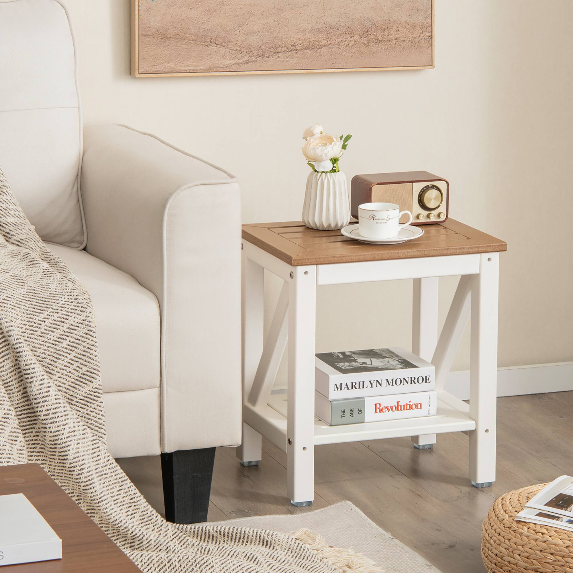 The image features a cozy living room setting with a white chair, a small table, and a coffee table. On the coffee table, there is a cup of coffee, a vase with flowers, and a book. The small table has a radio on it, and there is a book on the floor next to the chair. The scene is complemented by a painting on the wall, adding a touch of artistic flair to the room.
