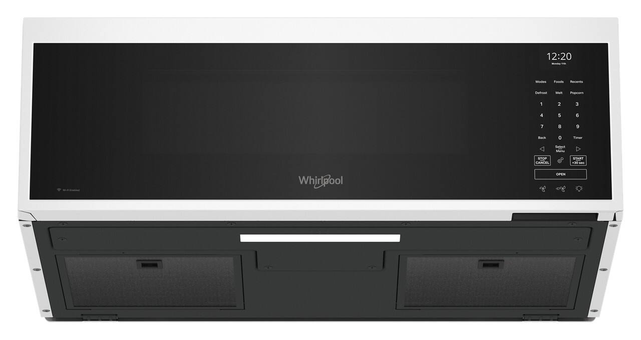 The image shows a black and white Whirlpool microwave oven with a digital display. The display shows the time as 12:20. The microwave has various buttons on the front, including a defrost button, a popcorn button, and a timer button. The oven is currently in the open position.