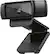 The image features a Logitech webcam with a black frame, which is mounted on a stand. The webcam is designed for use with a computer and has a built-in microphone. The stand is adjustable, allowing the user to position the webcam at an optimal angle for their needs. The webcam is capable of capturing high-definition video at a resolution of 1080p, providing clear and sharp images.
