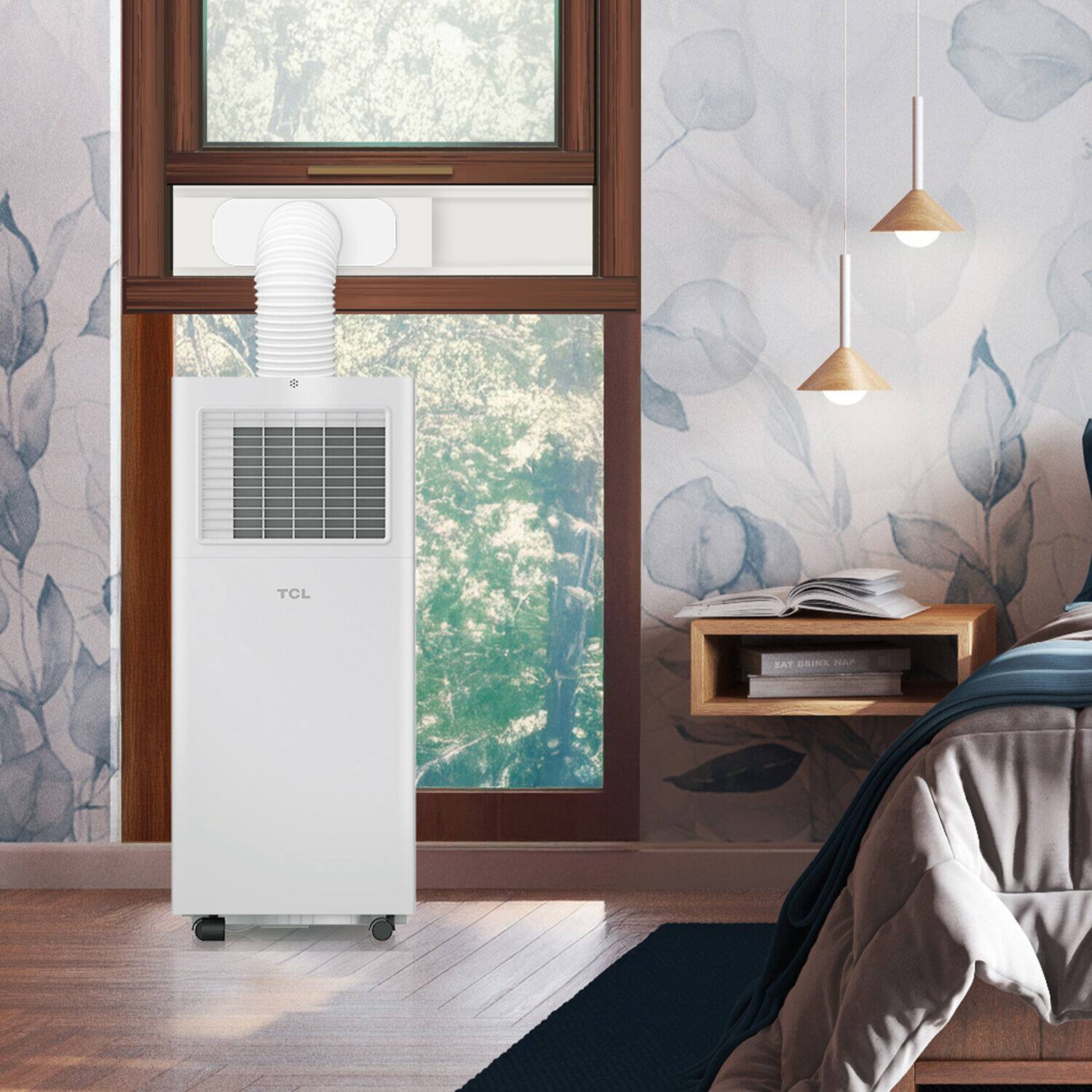 The image shows a bedroom scene with a bed, a window, and a TCL air conditioner. The air conditioner is placed near the window, and there is a book on the bed. The room also features a potted plant and a vase, adding to the cozy atmosphere.