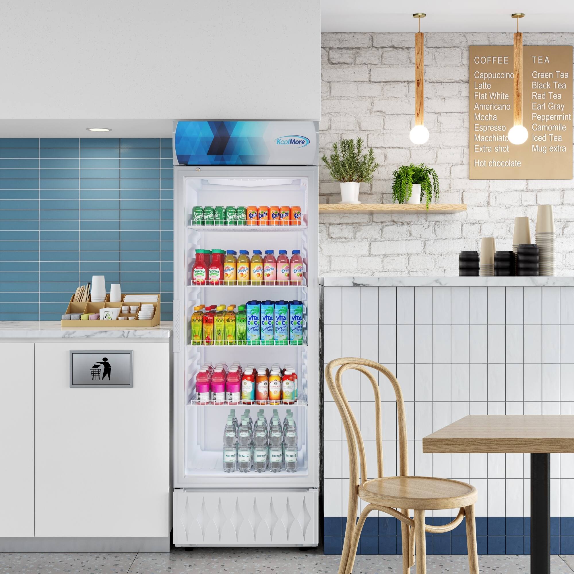 KooMore offers a variety of beverages, including coffee, tea, and hot chocolate. The options available are:

- Coffee: Americano, Black Tea, Cappuccino, Earl Gray, Espresso, Flat White, Green Tea, Latte, Macchiato, Mocha, Peppermint, Red Tea, and Extra Shot.
- Tea: Camomile, Hot Chocolate, and Extra Hot Chocolate.

In the image, there is a refrigerator filled with various drinks, including bottles of water and juice. The refrigerator is located next to a dining table with chairs, creating a comfortable and inviting atmosphere for customers to enjoy their beverages.