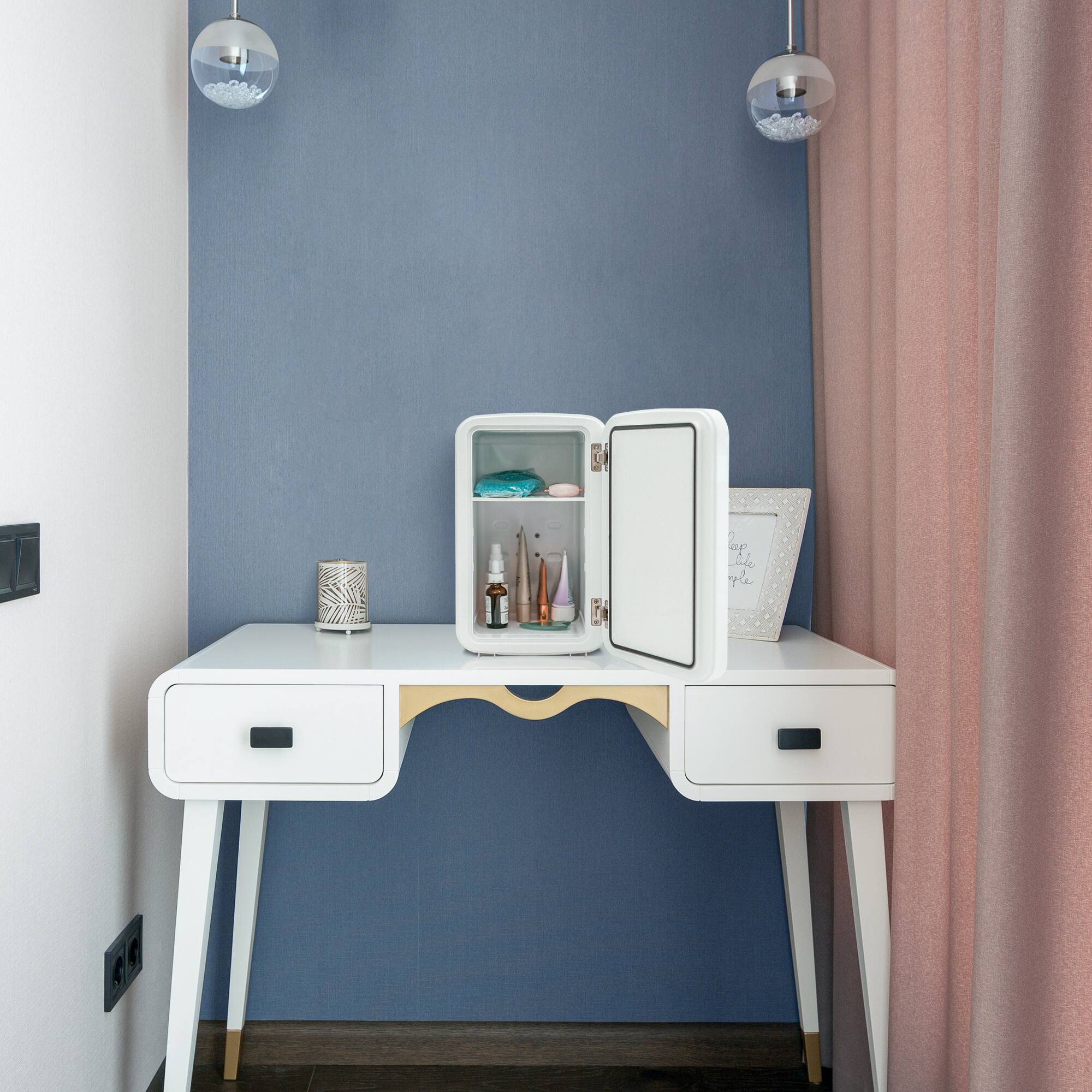 I'm sorry, but the text "ap uke qle" does not make sense and does not provide any context or information about the image. The image shows a white desk with a mirrored door, a white drawer, and a small white cabinet. The desk is situated in a corner of a room, and there are two lights above it.