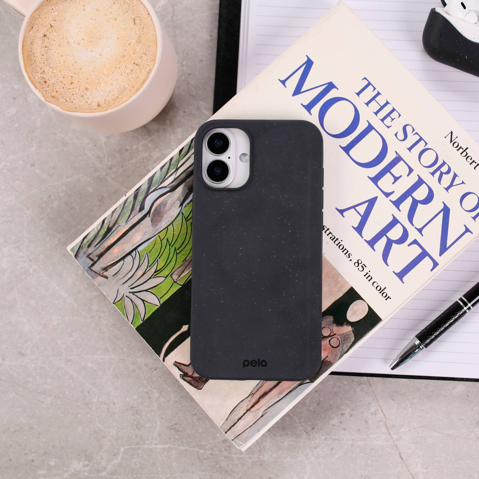 The Modern Story by Norbert O. Pecklins is a book about art and its history. The book is placed next to a coffee mug and a cell phone case. The cell phone case is black and has a camera design on it.