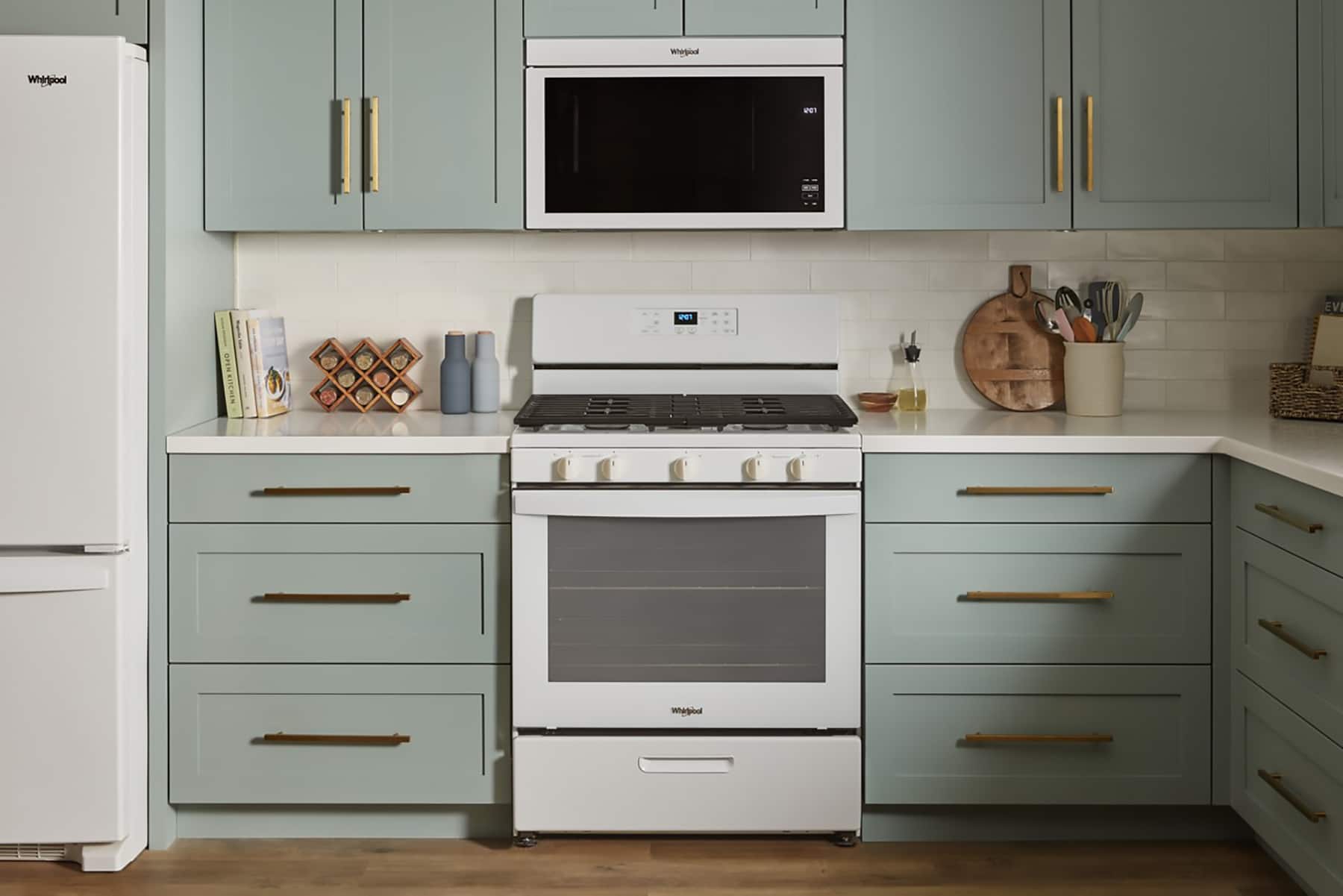 In the image, there is a kitchen featuring a white refrigerator and a white stove. The stove has a microwave above it, and there are several knives and a bowl placed on the counter. The kitchen is equipped with a sink, and there is a book on the counter as well. The overall scene is a well-organized and functional kitchen space.