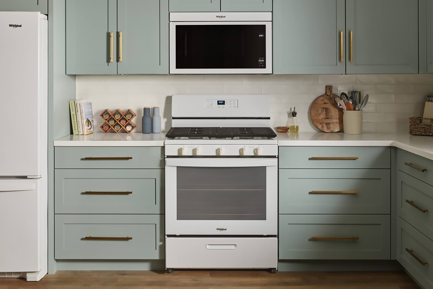 In the image, there is a kitchen featuring a white refrigerator and a white stove. The stove has a microwave above it, and there are several knives and a bowl placed on the counter. The kitchen is equipped with a sink, and there is a book on the counter as well. The overall scene is a well-organized and functional kitchen space.