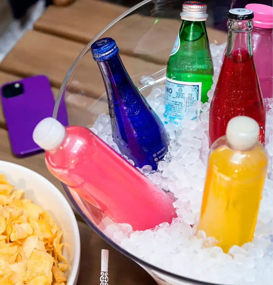 A bowl of ice with four bottles of soda in it.