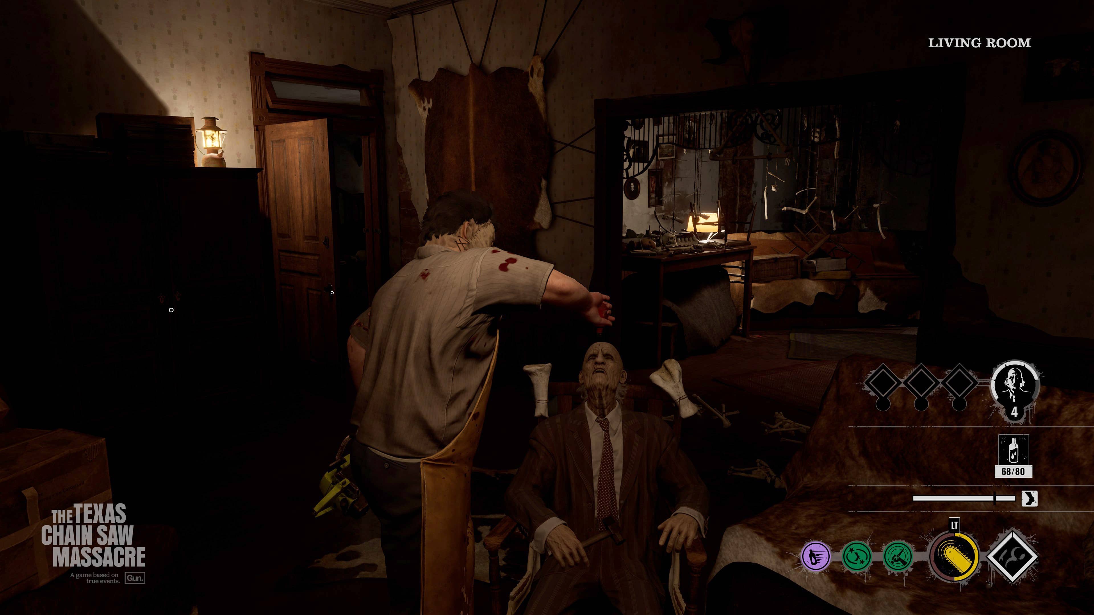 The image is a screenshot from a video game called "The Texas Chain Saw Massacre." The scene takes place in a living room, where a man is holding a gun and pointing it at another man who is sitting on a chair. The game appears to be set in a dark environment, adding to the tense atmosphere.