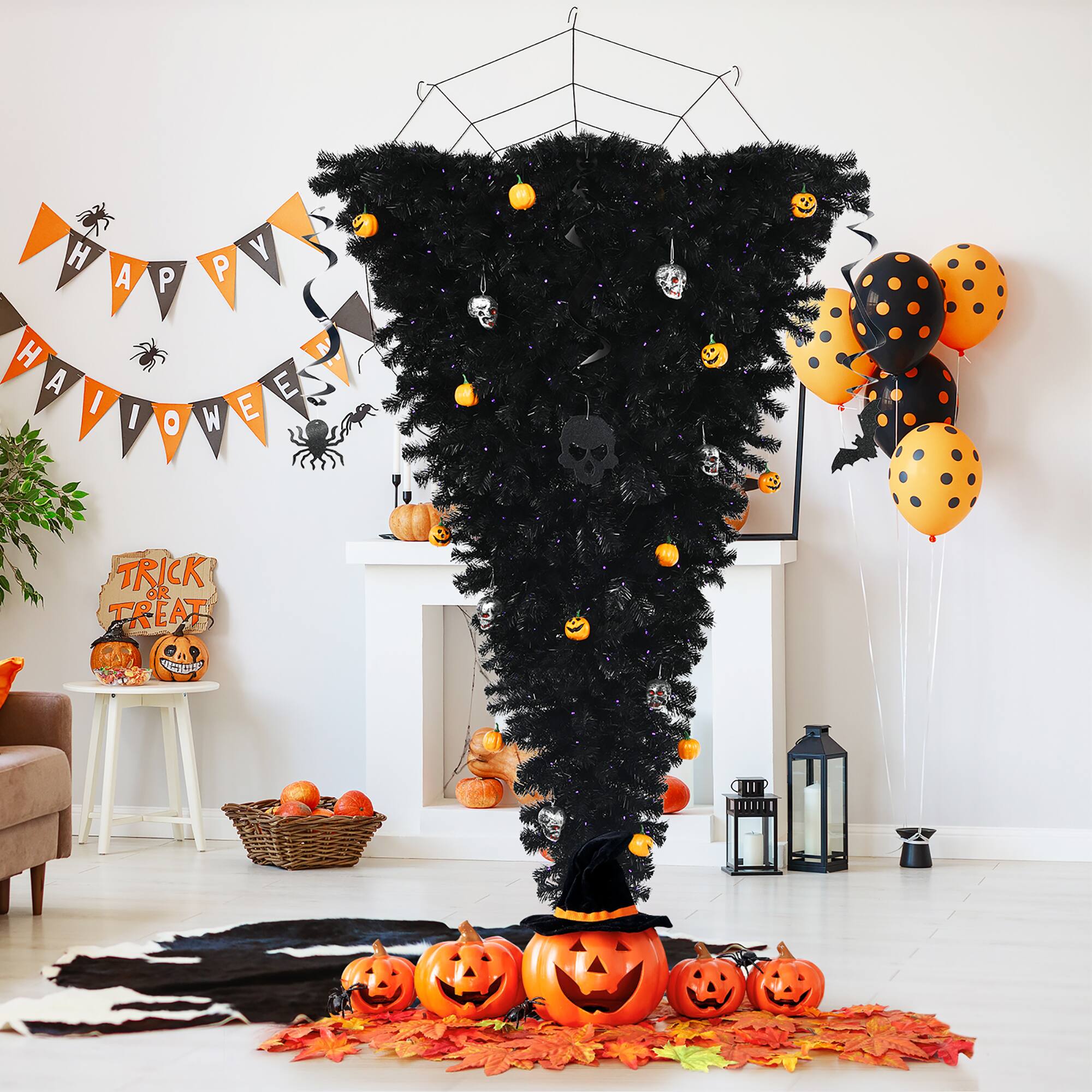 Halloween decorations are displayed in the living room. There is a black tree with orange and purple decorations, including a witch's hat. The room also features a pumpkin, a spider web, and a basket of oranges. The decorations create a festive atmosphere for the holiday.