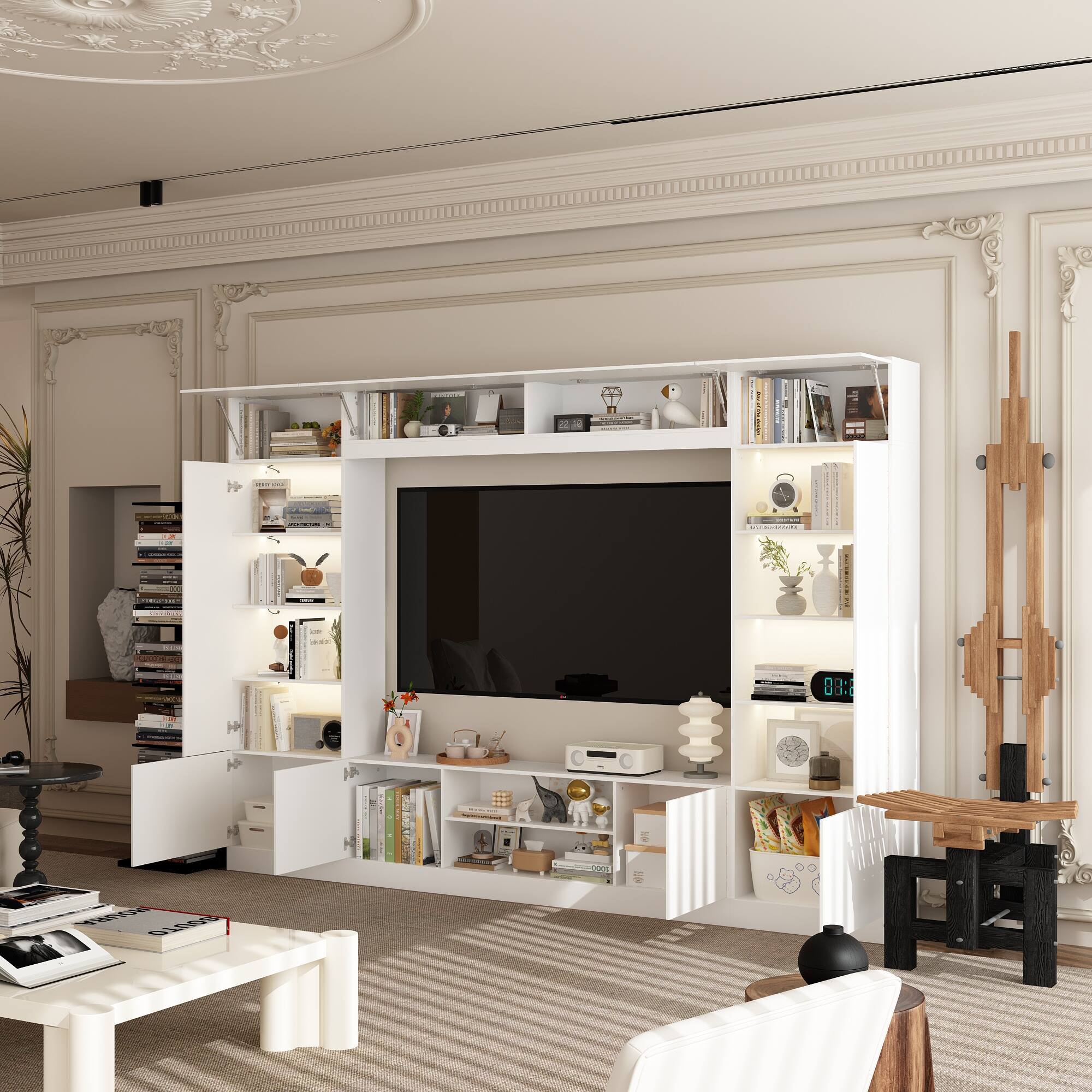 The living room is white and has a large flat screen TV on the wall. There are shelves on either side of the TV, and a couch is positioned in front of it. The room also features a coffee table and a potted plant. The living room is well-decorated with a variety of books and vases, creating a cozy and inviting atmosphere.