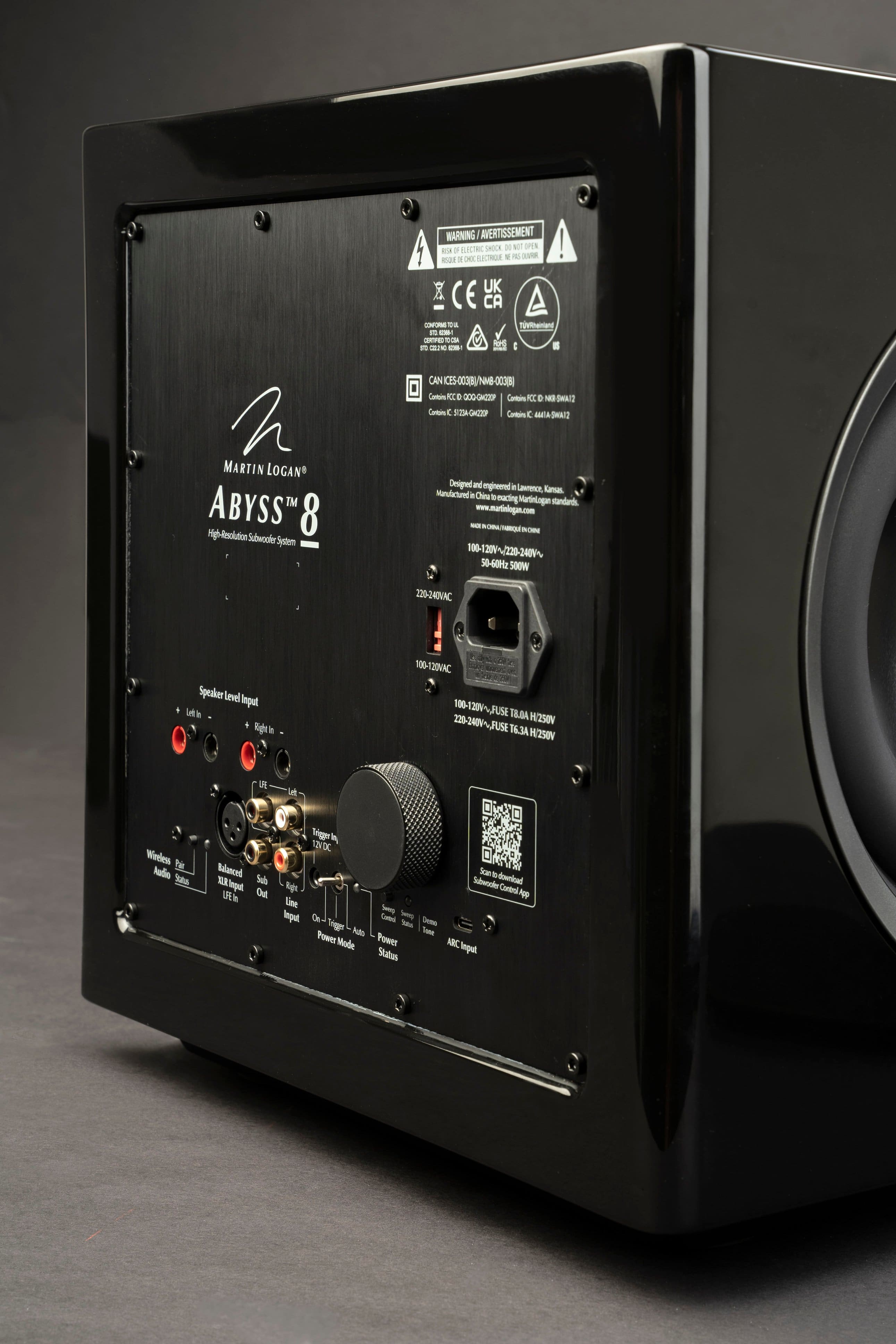 The image features a black Abyss 8 subwoofer system designed and manufactured by Martin Logan. The subwoofer is designed for 100-120V~/220-240V 50-60Hz 500W 220-240VAC speaker input. The back of the subwoofer has a warning label and a fuse tab. The subwoofer is made in China and is available in black.