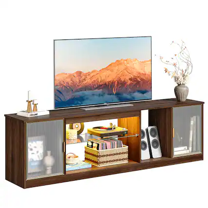 The image features a wooden entertainment center with a flat screen TV on top. The TV is displaying a beautiful mountain scene. The entertainment center also has a collection of books, CDs, and a vase with flowers. The books are arranged in a neat stack, while the CDs are placed nearby. The vase with flowers adds a touch of elegance to the scene. The entertainment center is a perfect place to relax and enjoy various forms of entertainment.