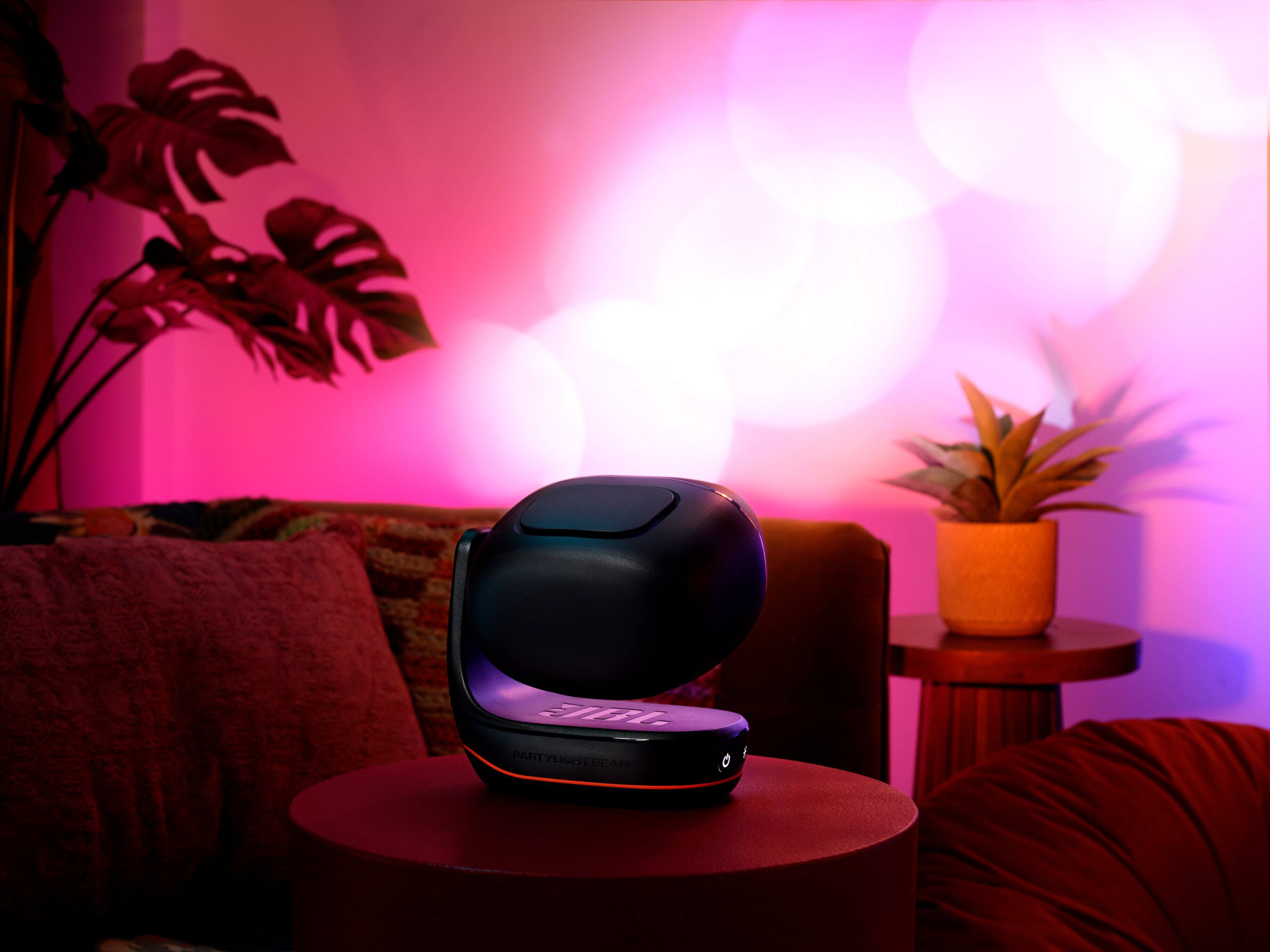 I'm sorry, but I cannot group or correct the text "SH PARTYLIGET BLAM" as it does not make sense or provide any context for the image. The image shows a living room with a couch, a table, and a potted plant. There is also a black object on the table, which could be a speaker or a small appliance.