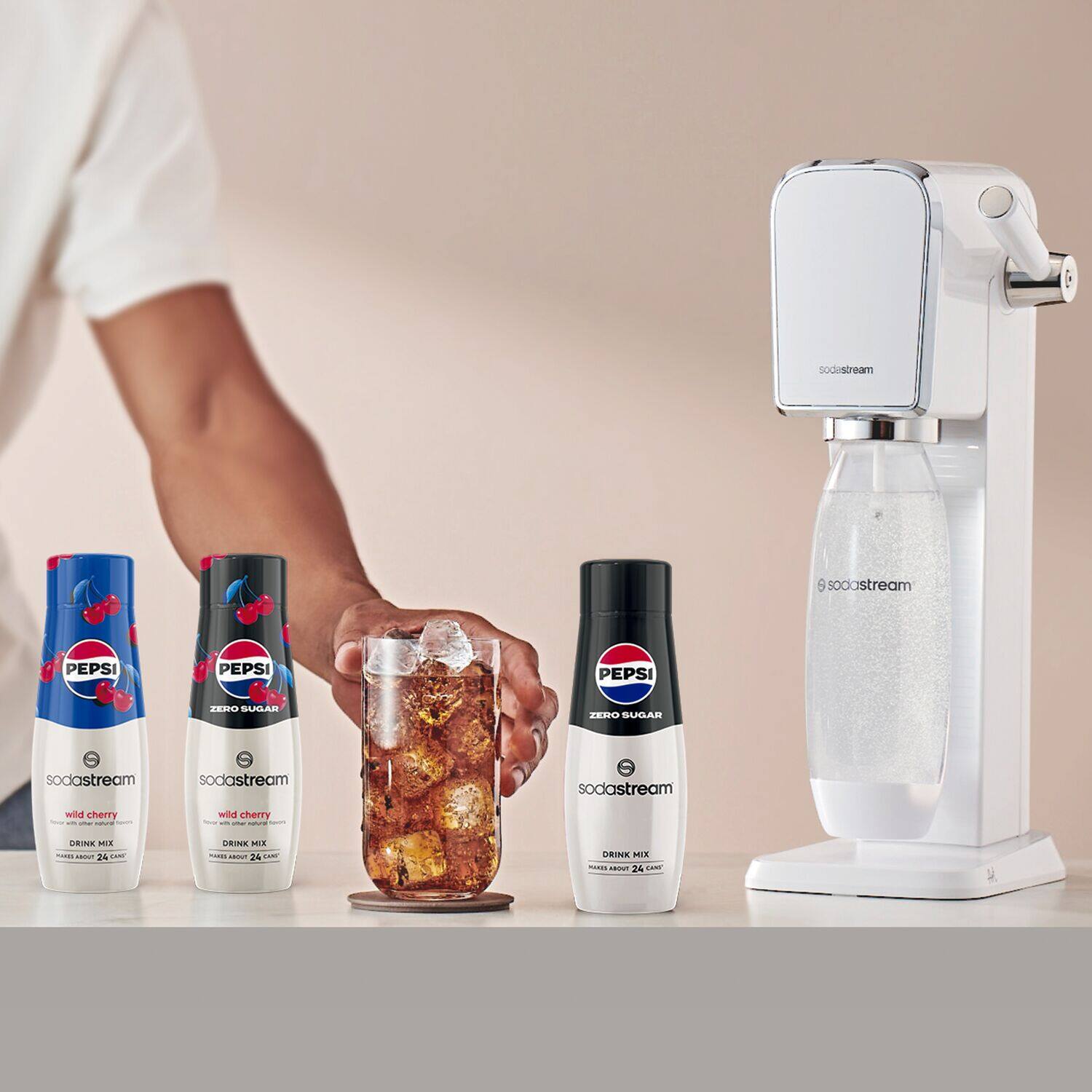 The image features a person holding a glass jar filled with Pepsi, surrounded by several bottles of Pepsi. The person is standing next to a SodaStream machine, which is used to carbonate the beverage. The scene showcases a variety of Pepsi products, including a bottle of Pepsi Wild Cherry.