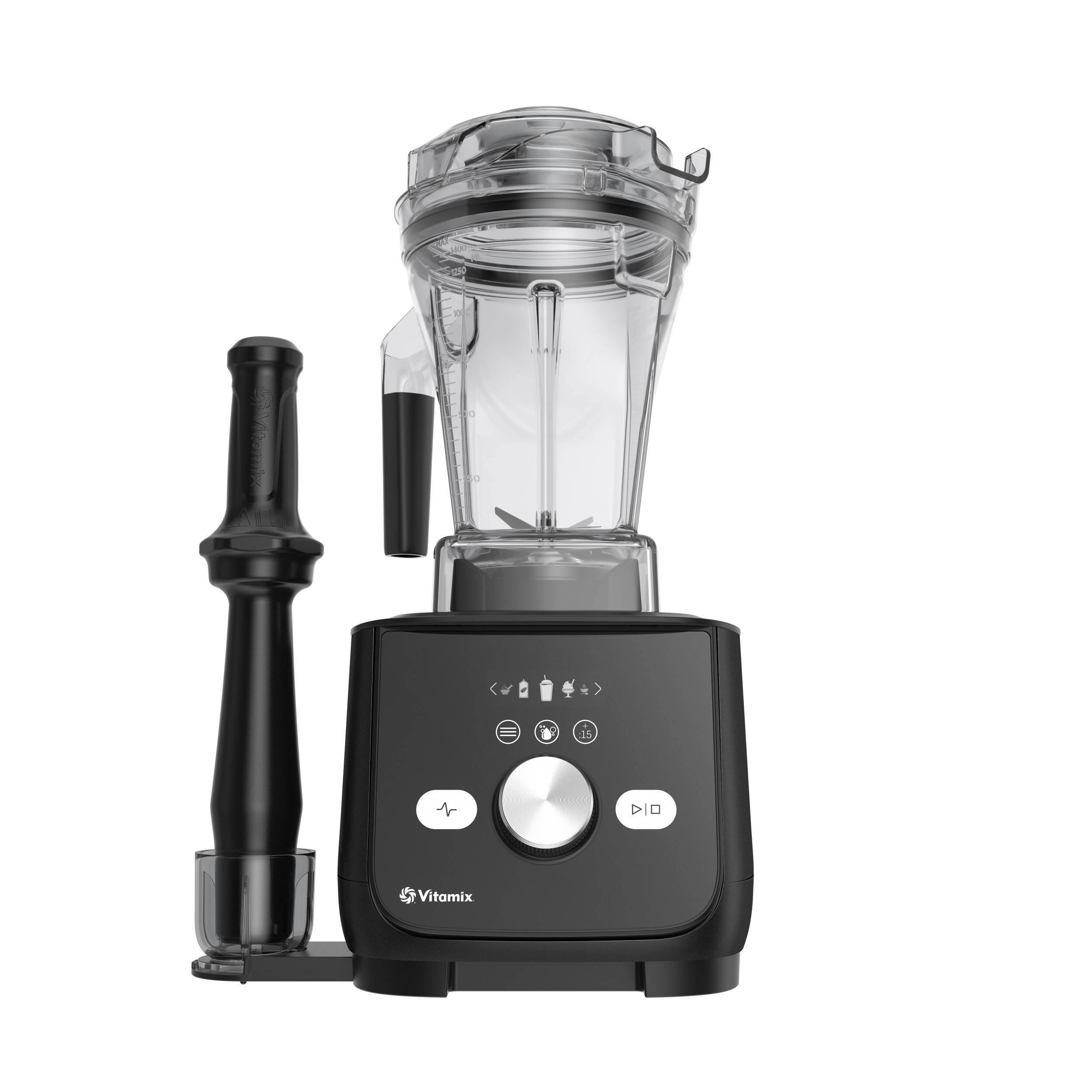 The image features a Vitamix blender with a black base and a clear container. The blender is turned on, and the lid is off. It is accompanied by a black and silver blender stick, which is placed next to the blender. The blender is designed for easy operation and efficient blending of various ingredients.