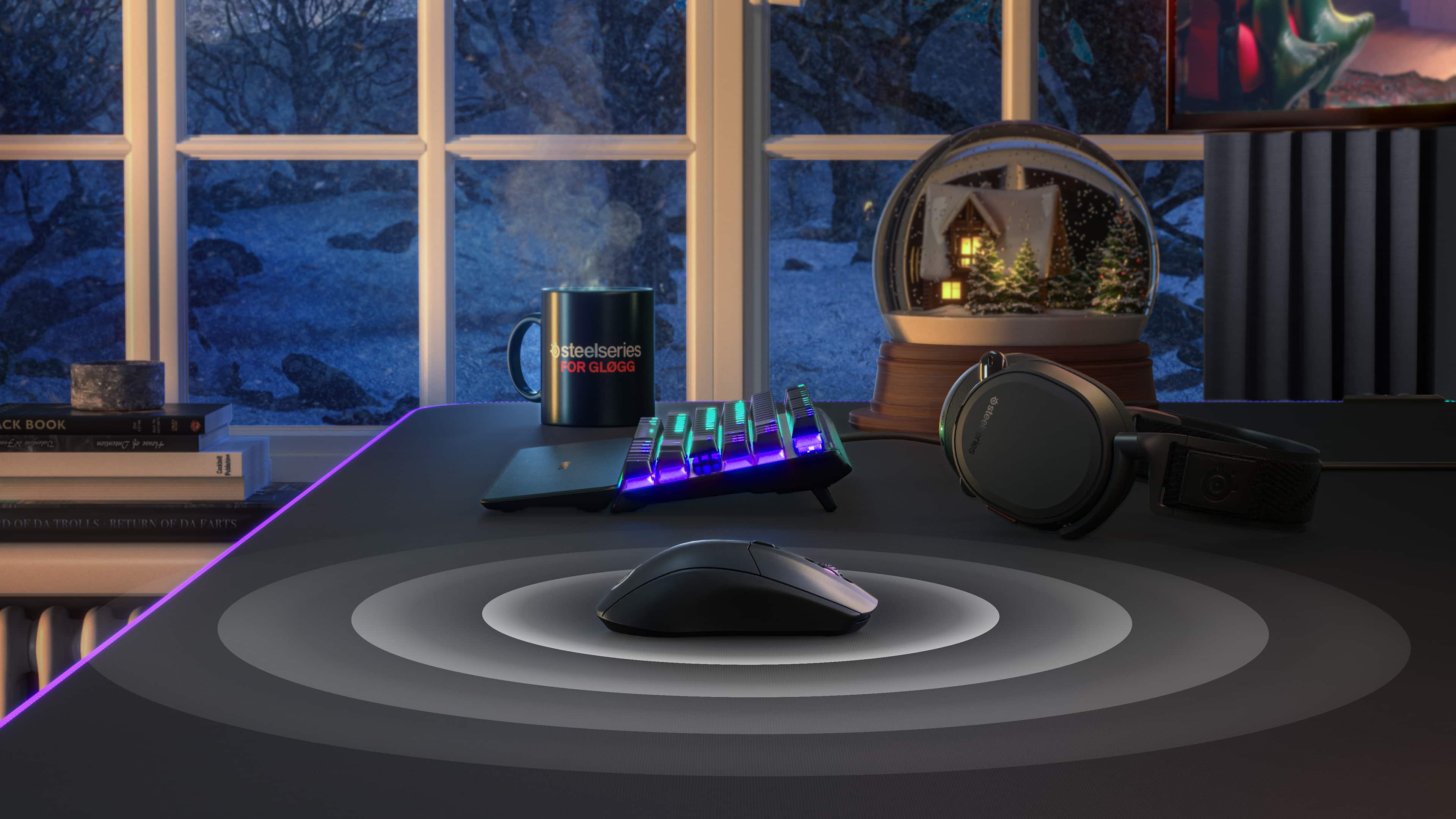 The image shows a computer desk with a mouse and keyboard on it. The mouse is placed in front of a coffee mug, and there is a cup of coffee next to it. The keyboard is located in front of the mouse, and a cell phone is placed nearby. The desk is situated in front of a window, providing a view of the snowy landscape outside.