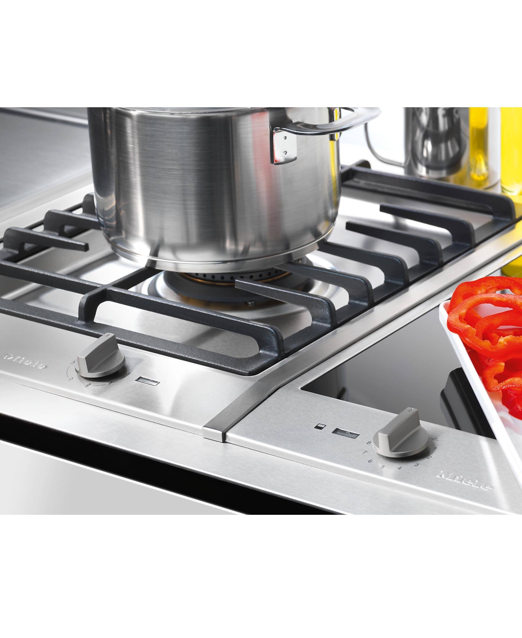 I'm sorry, but I cannot group or correct the text "0olo a F J e 2 MIGLE" as it does not appear to be related to the image. The image shows a stove with a pot on it, and there are peppers nearby.