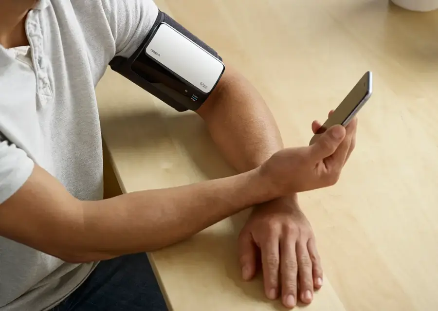 "The man is holding a cell phone and a blood pressure monitor."