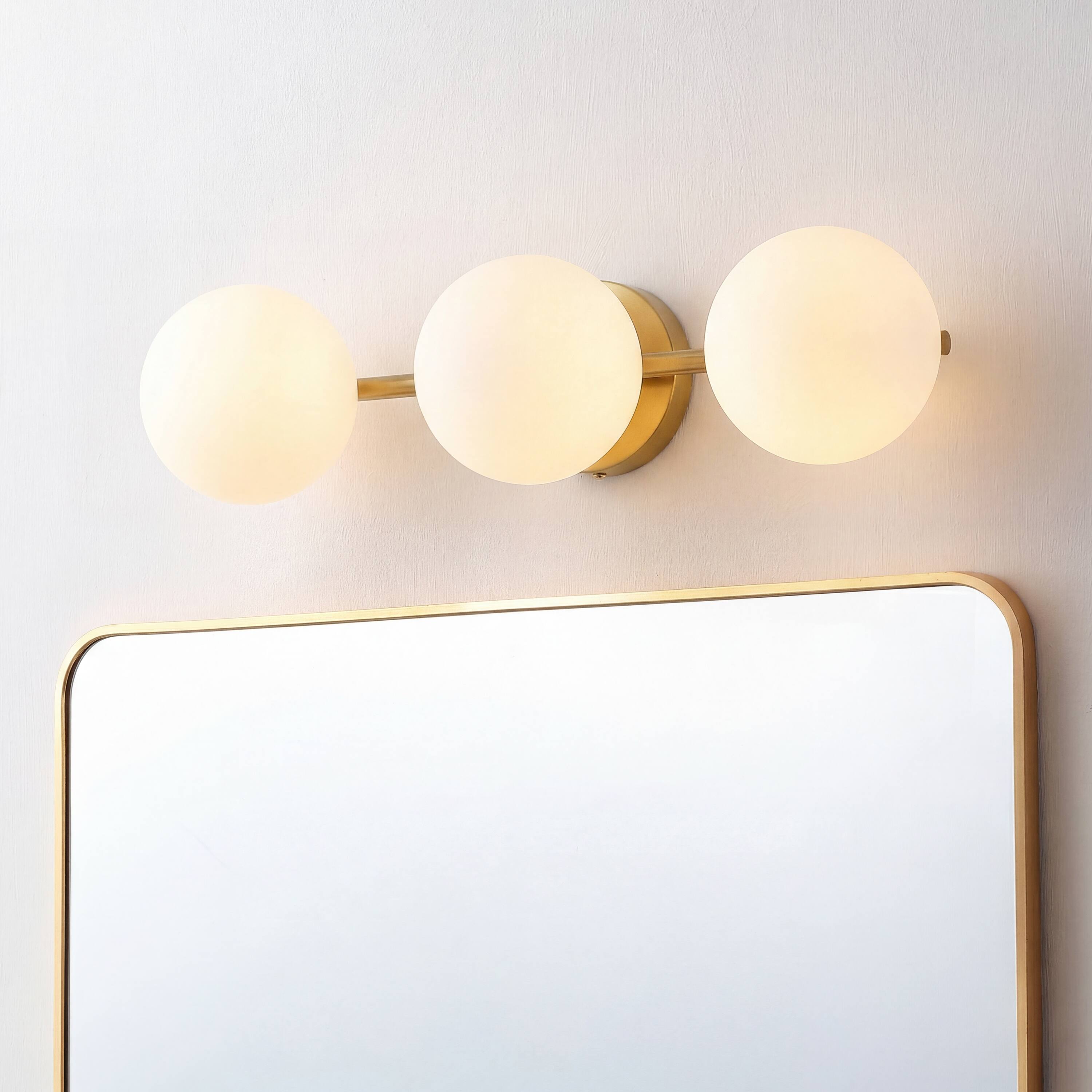 Alt View 1. Jonathan Y - Nash 23" Mid-Century Modern Brass Gold 3-Light Metal Vanity Light with White Glass Globe Shades Wall Sconce - Brass Gold.