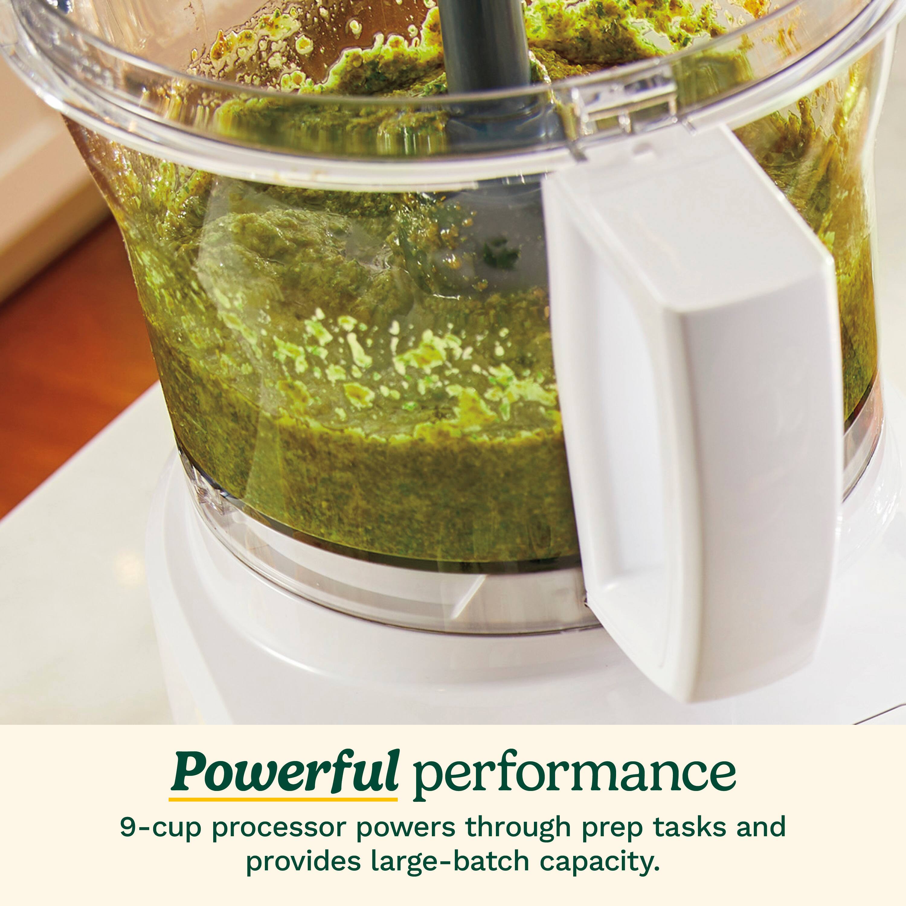 The image features a blender filled with green food, likely a smoothie or a green mixture. The blender is described as having a powerful performance, with a 9-cup processor that can handle prep tasks and provide large-batch capacity. This implies that the blender is capable of handling various tasks, from making small batches to large ones, and can efficiently blend different types of food.