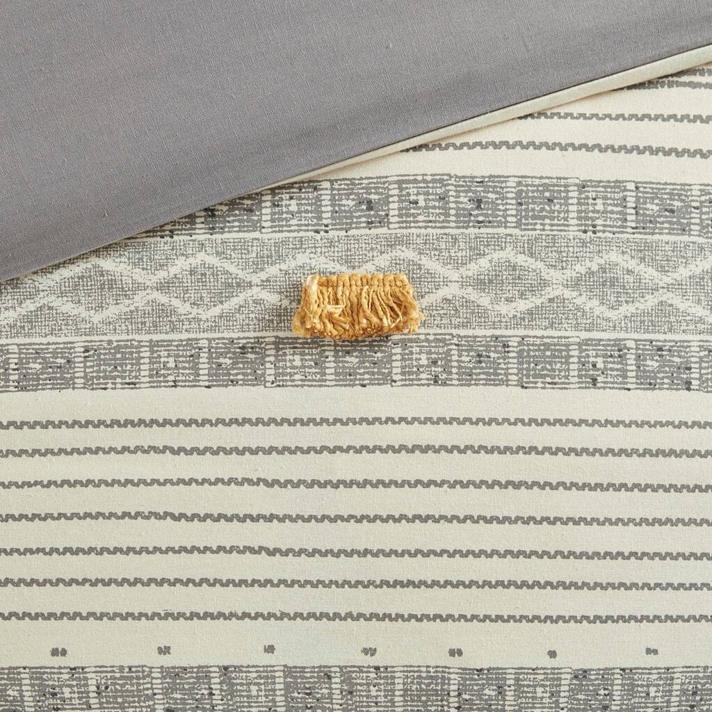 The text in the image appears to be a patterned design, possibly for fabric or wallpaper. It includes a mix of geometric shapes and lines. There is no clear, readable text to correct or group. The image shows a piece of fabric with a textured pattern and a small decorative item on top.