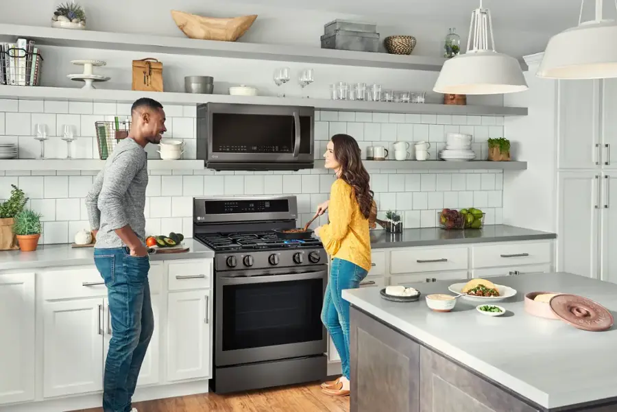 I'm sorry, but the text you provided does not make sense or provide any context for the image. The image shows a man and a woman standing in a kitchen, with the woman standing next to a stove. They seem to be engaged in conversation or preparing a meal together. The kitchen is well-equipped with various appliances and items, such as a microwave, oven, and multiple bowls and cups.