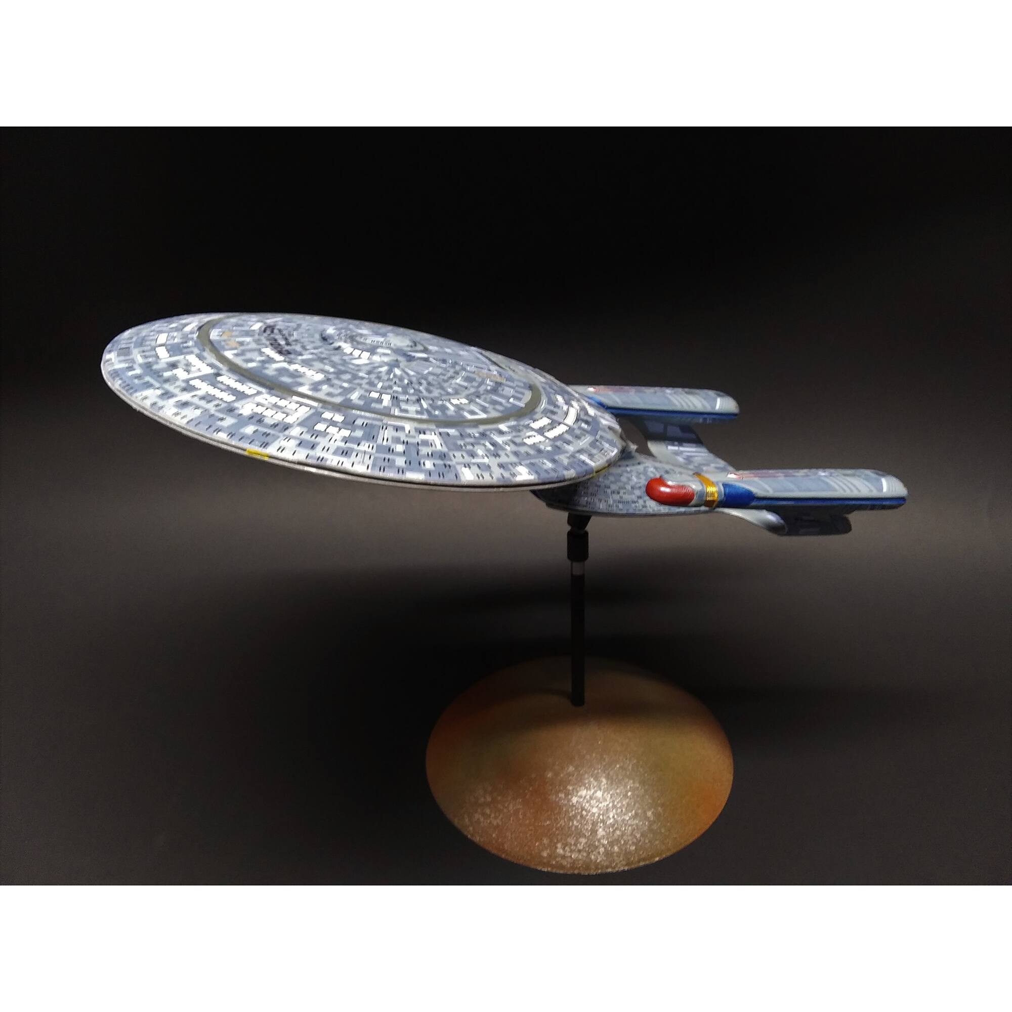 I'm sorry, but the text "E - PS arpada AAAR C2E" does not appear in the image. The image features a blue and white model of a spaceship, possibly a Star Trek ship, sitting on a stand.