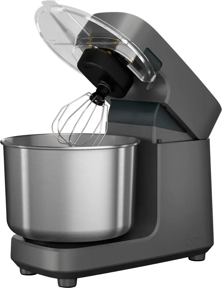 The image shows a silver kitchen appliance, possibly a food processor or blender, with a black motor. The appliance is in the process of mixing or blending something, as evidenced by the whirring motion of the motor. The appliance is placed on a countertop, and its design and function suggest that it is used for preparing various types of food.