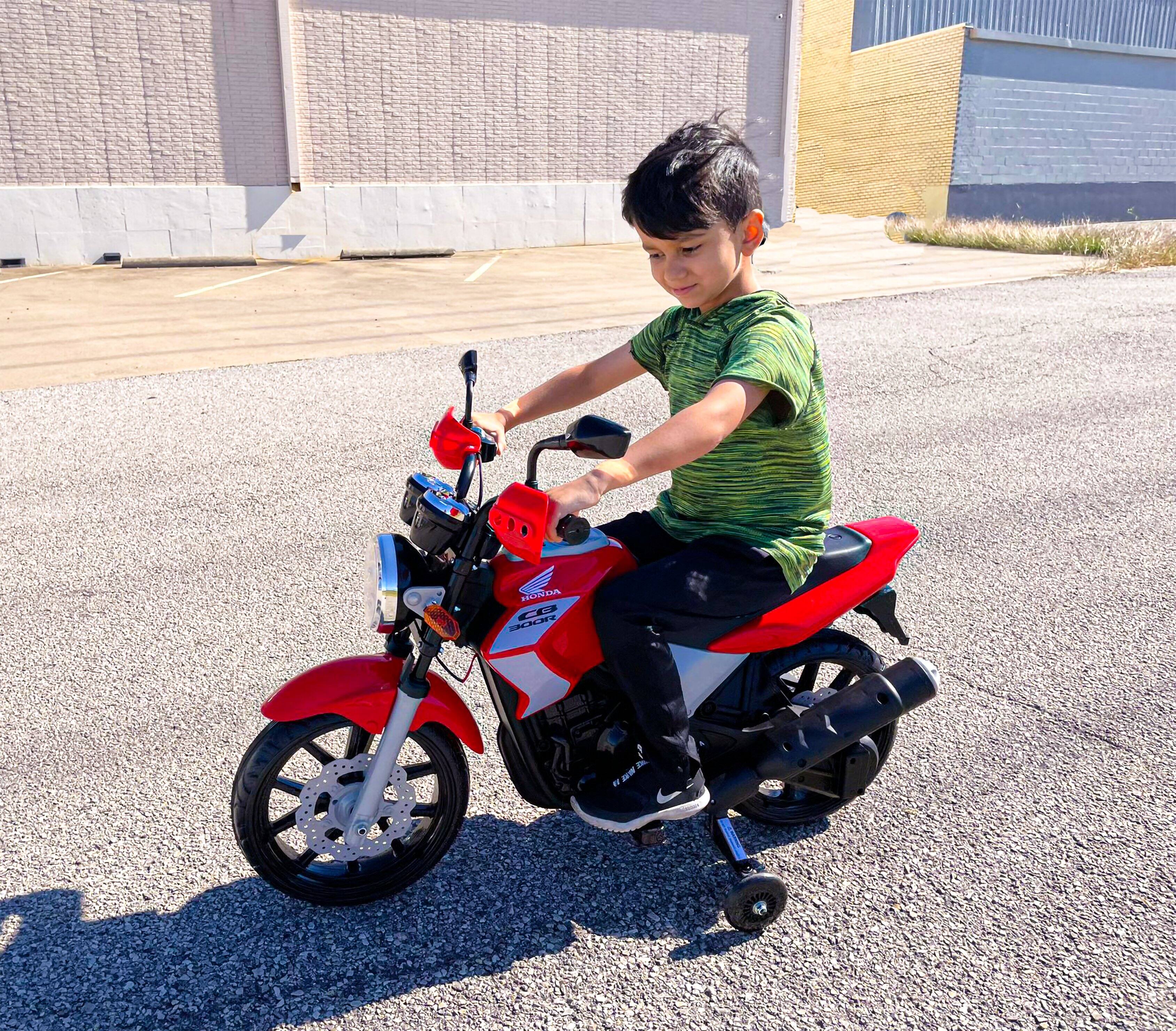 I cannot group or correct the text as it does not appear to be coherent or related to the image. The image shows a young boy riding a red motorcycle on the street.