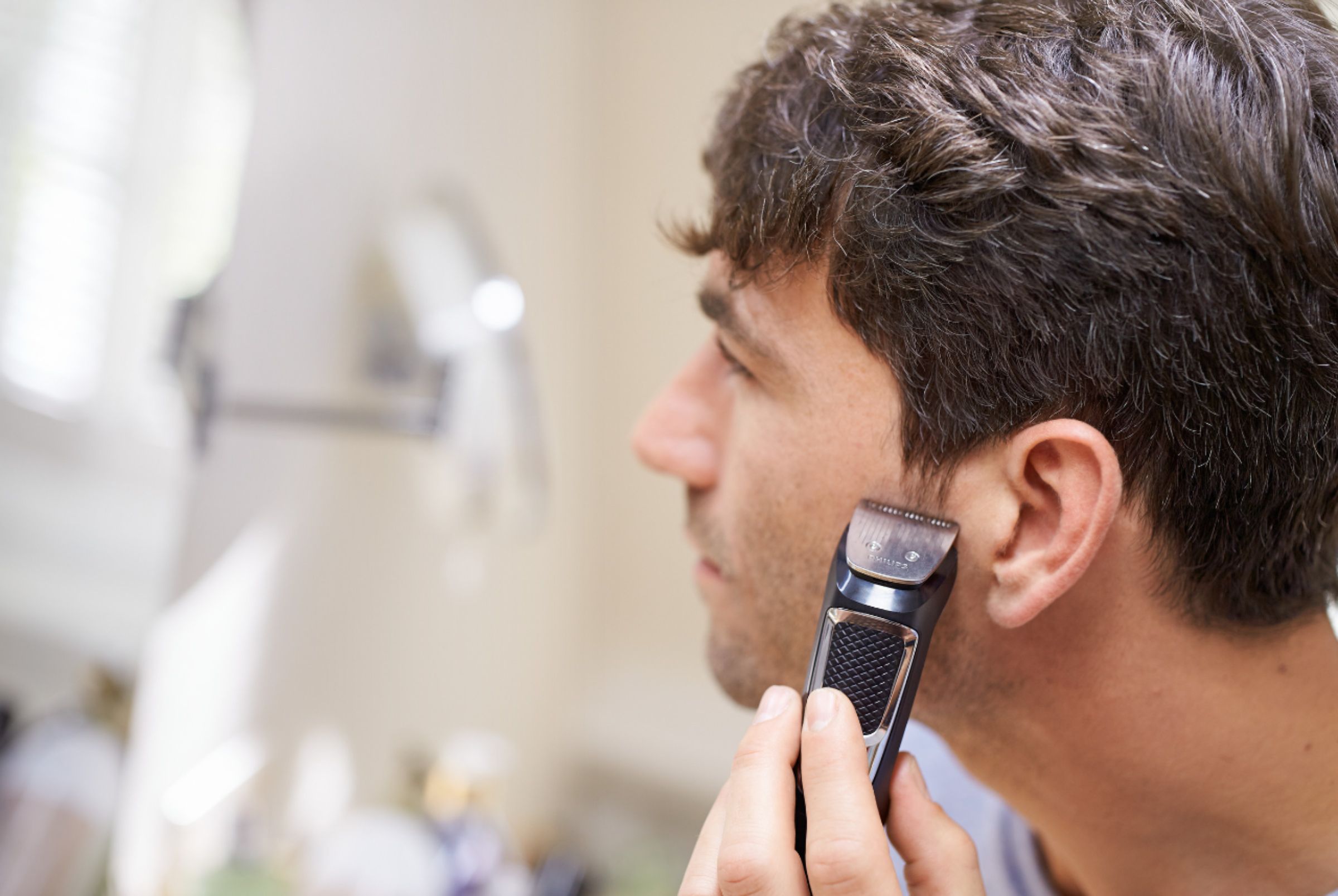 man using a beard trimmer to shape his sideburns